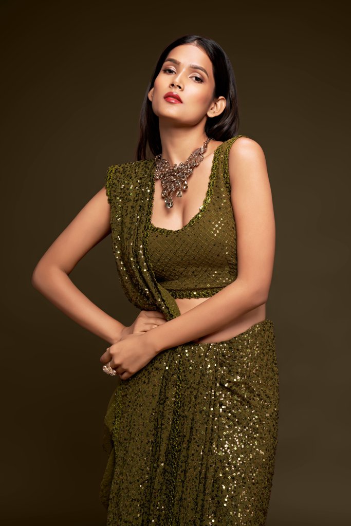 Rich olive sadi showcasing intricate sequins work, a stylish choice among the latest sarees for any occasion.