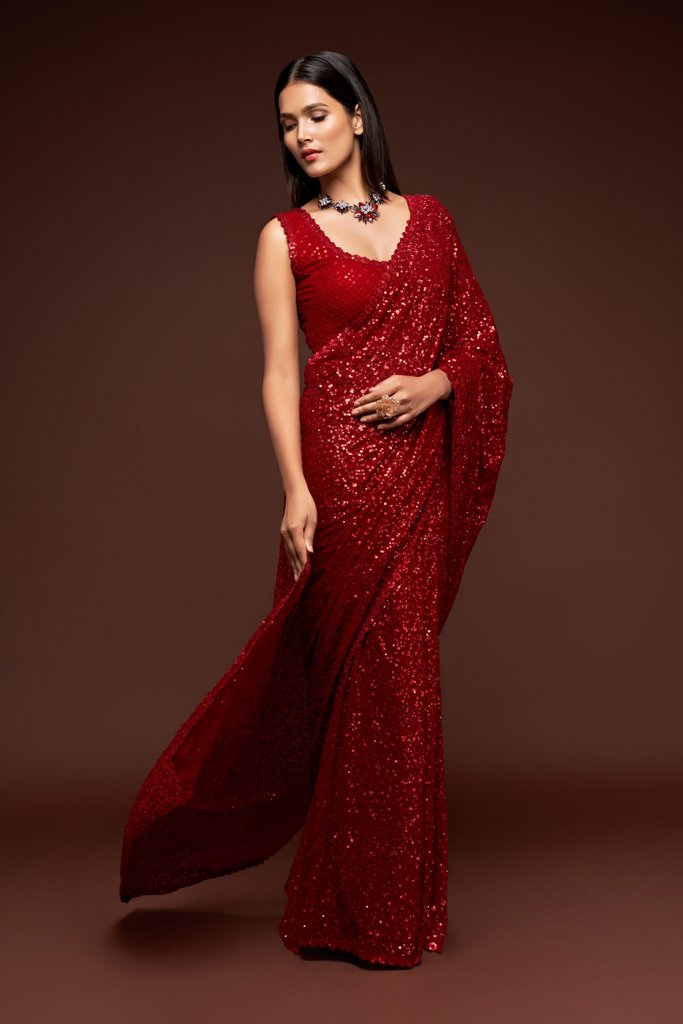 Elegant ruby red Indian sari draped gracefully, featuring shimmering sequins detailing for a glamorous look at parties.