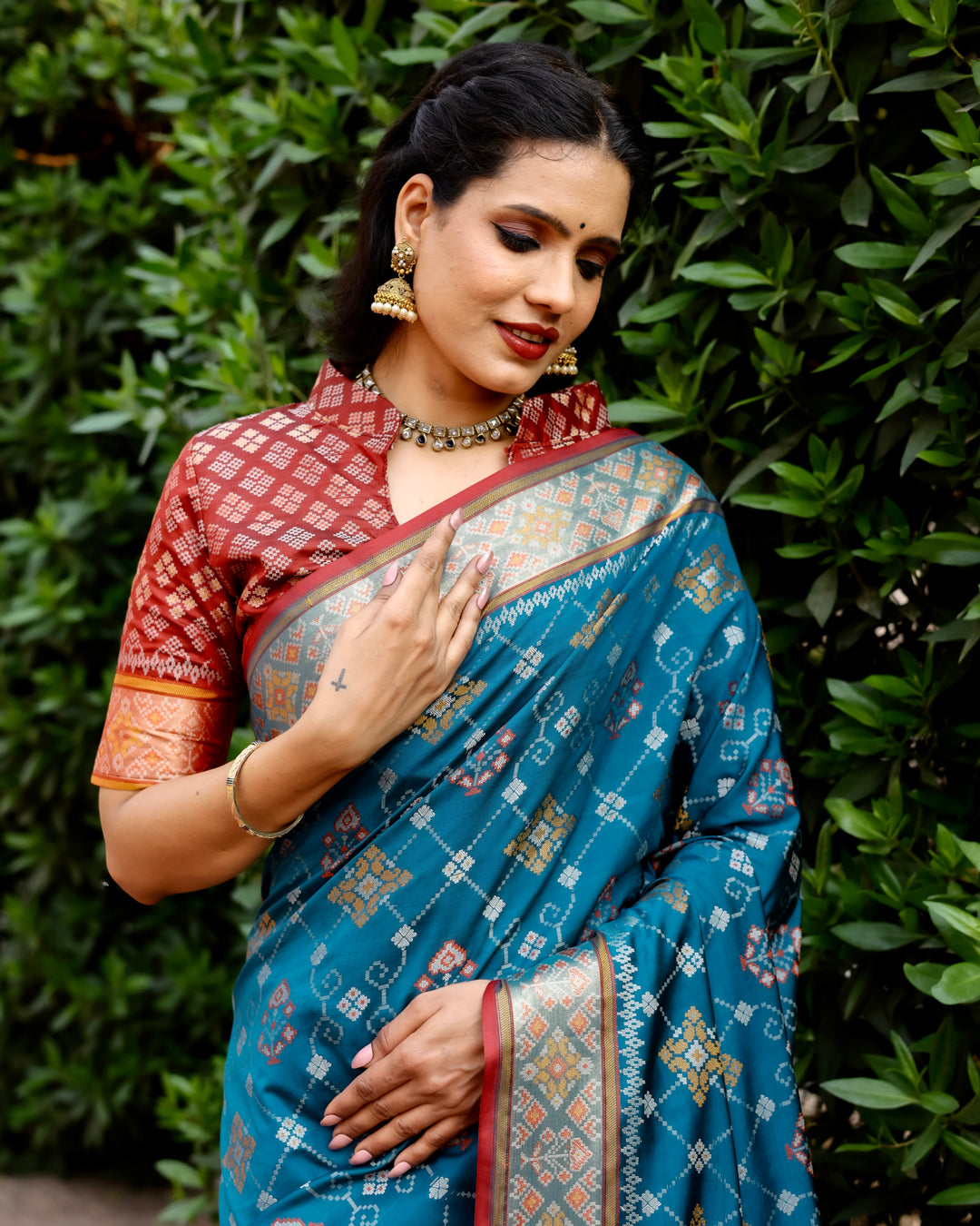 Add a touch of tradition with this teal Ikkat Patola silk saree, showcasing stunning Zari work and intricate Ikkat designs across the body.