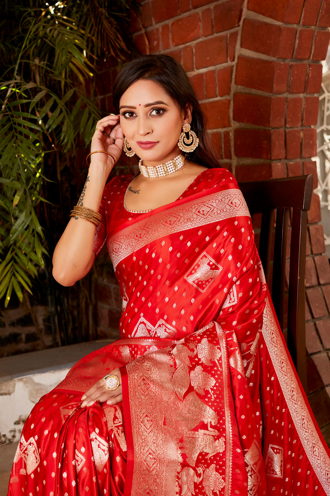 Beautiful red Kanjivaram satin silk saree with shimmering fabric and intricate butta work, perfect for making a statement at weddings.