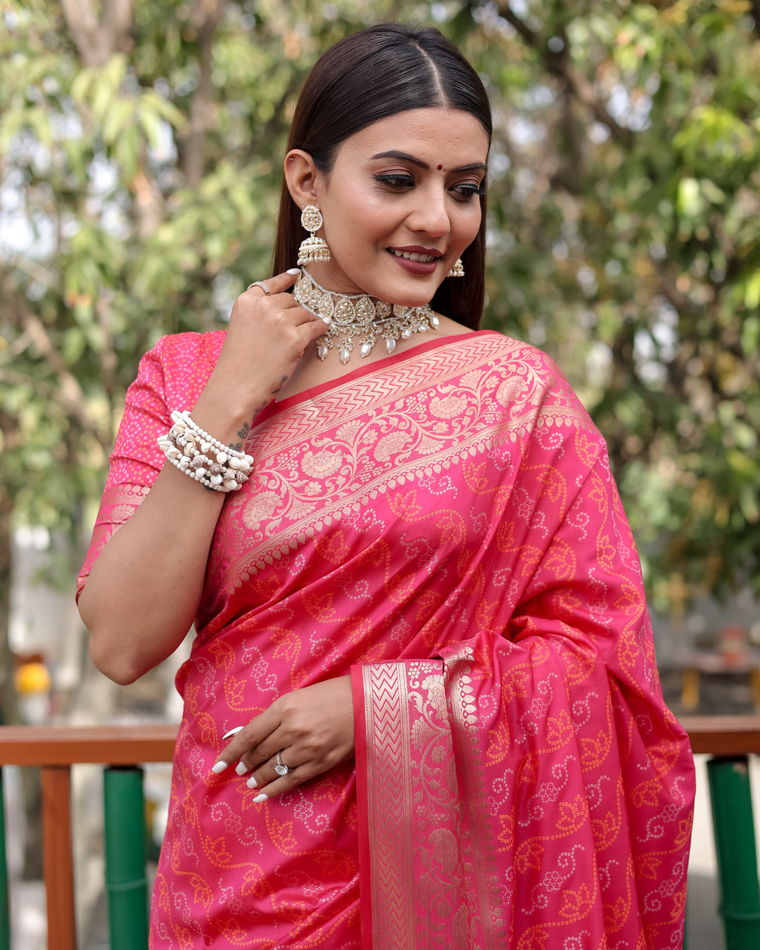 Vibrant bright-pink Bandhej Patola saree with stunning zari detailing and Kanchi borders, ideal for festive occasions.