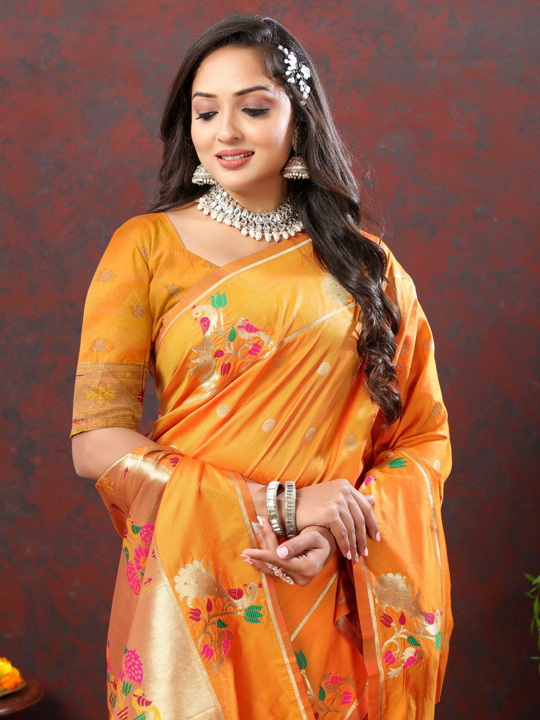 Bright orange Paithani silk saree with gold zari motifs and Meenakari border for grand occasions.