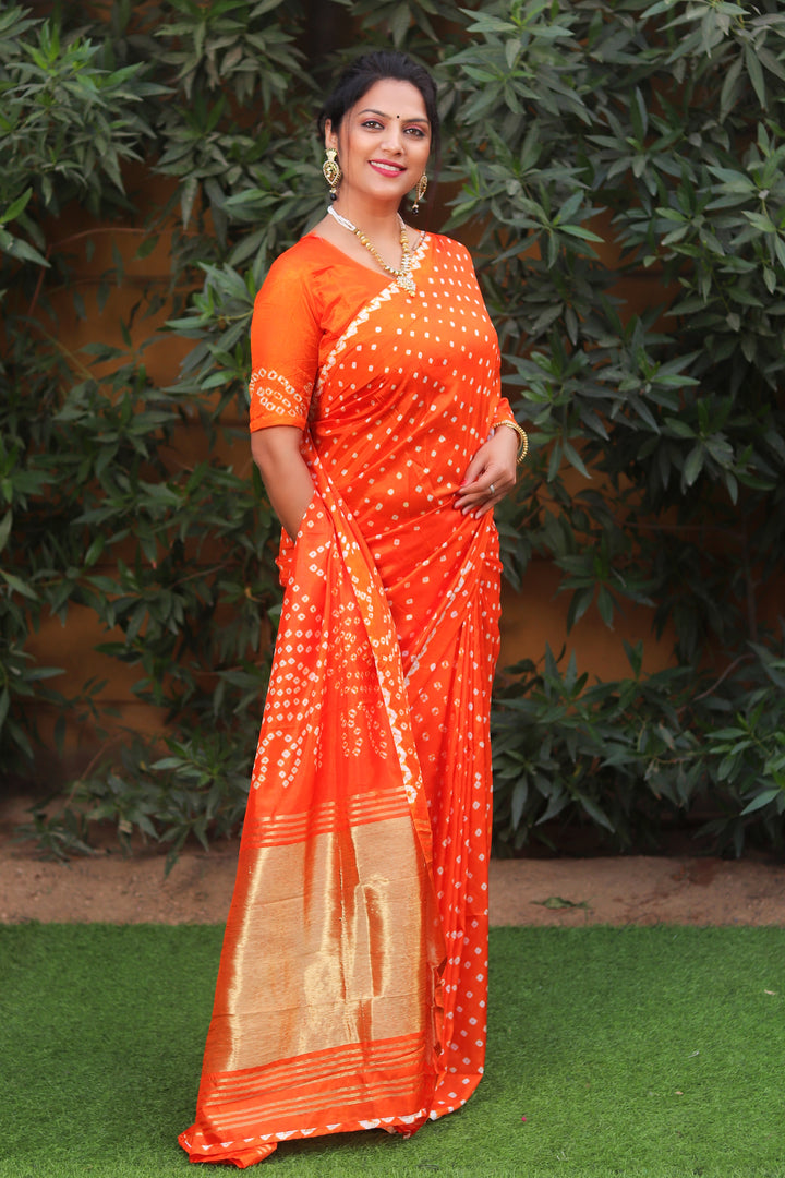 Bright orange Bandhej silk saree featuring traditional Bandhej art with Zari pallu for a unique and stylish look.