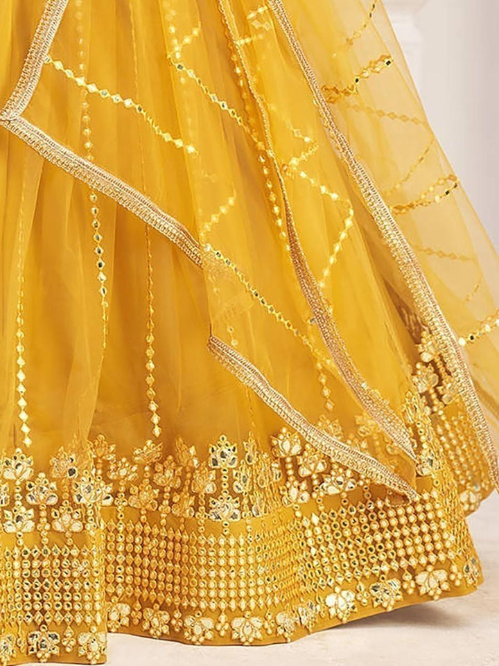 Mustard yellow net lehenga with sequins and lace for a traditional look.