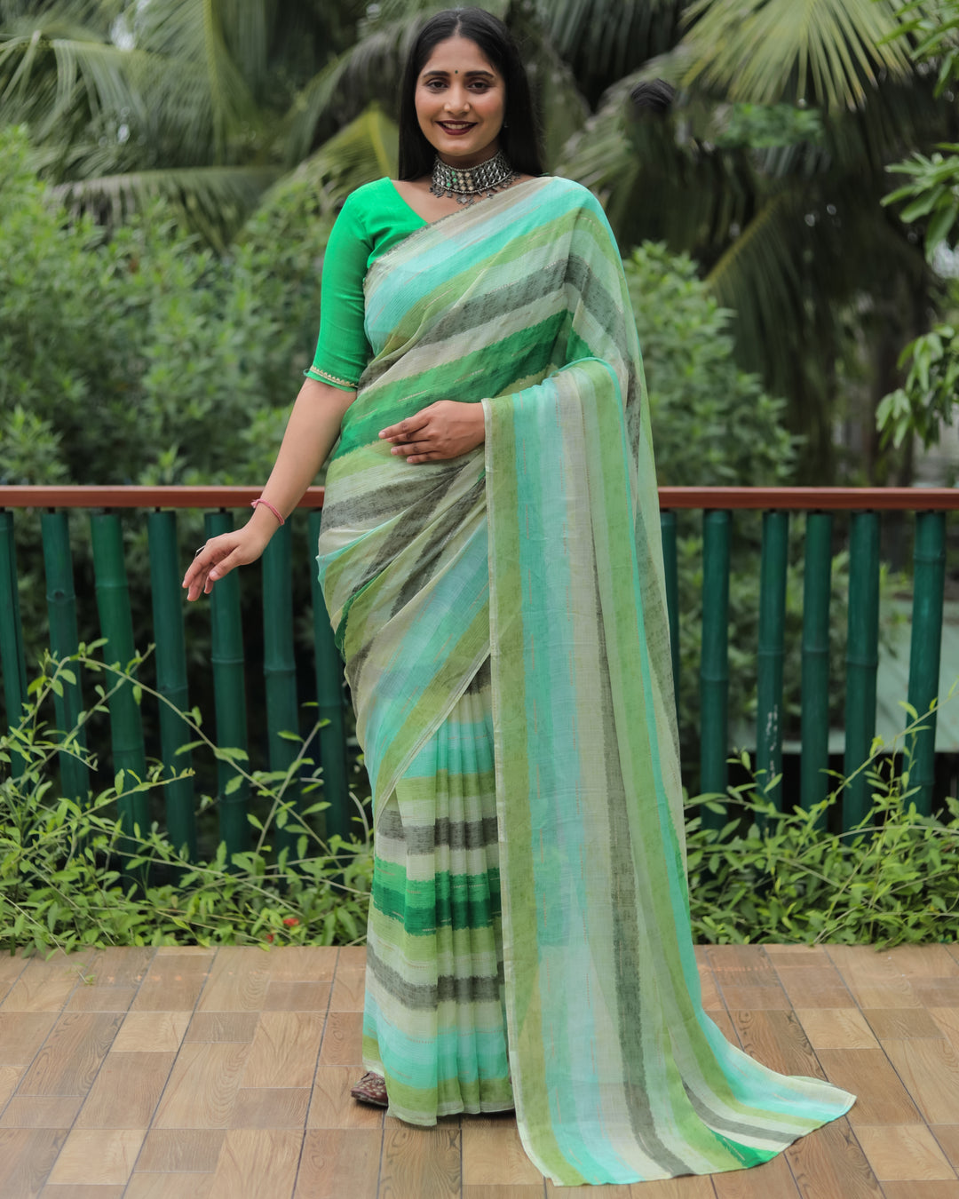 This green Moss chiffon saree with shimmering gold foil detailing and an all-over print brings timeless elegance to any occasion.