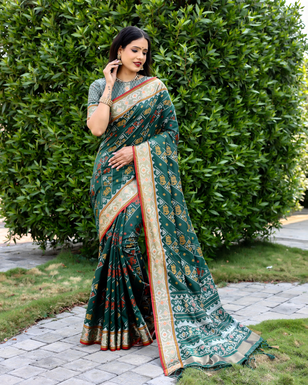 Elegant dark-green Bandhej silk saree with matching blouse and zari woven pallu, perfect for grand occasions.