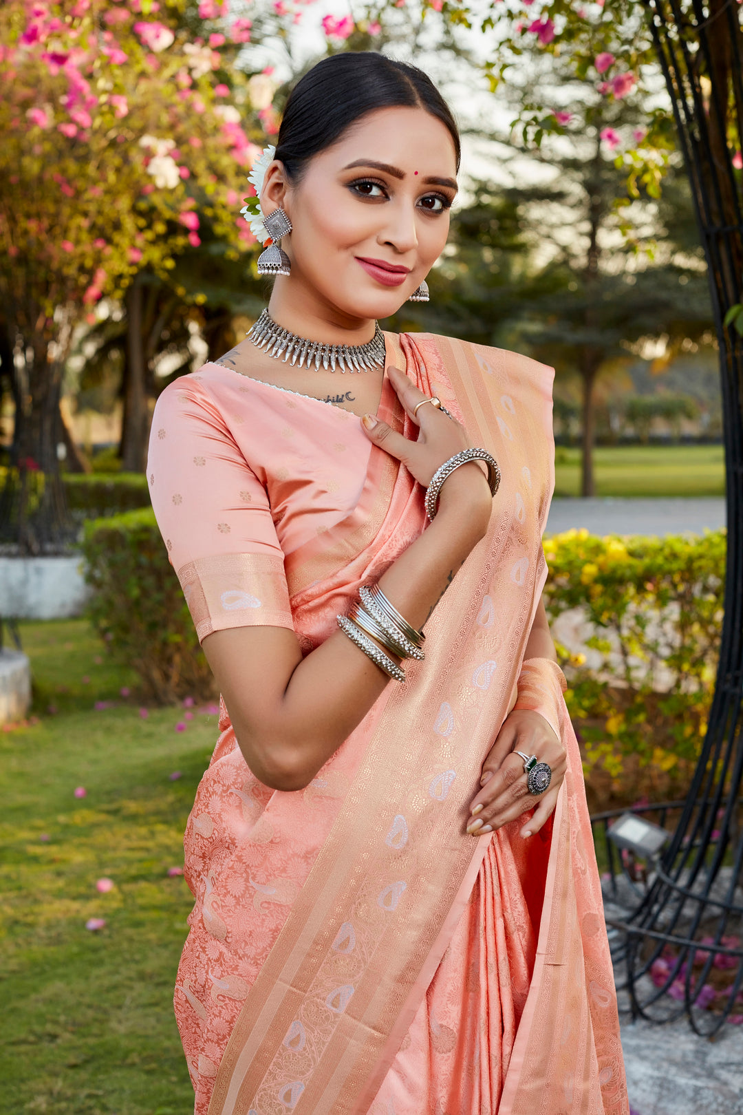 Soft peach Kanjivaram satin silk saree with intricate butta design and woven pallu, perfect for weddings.