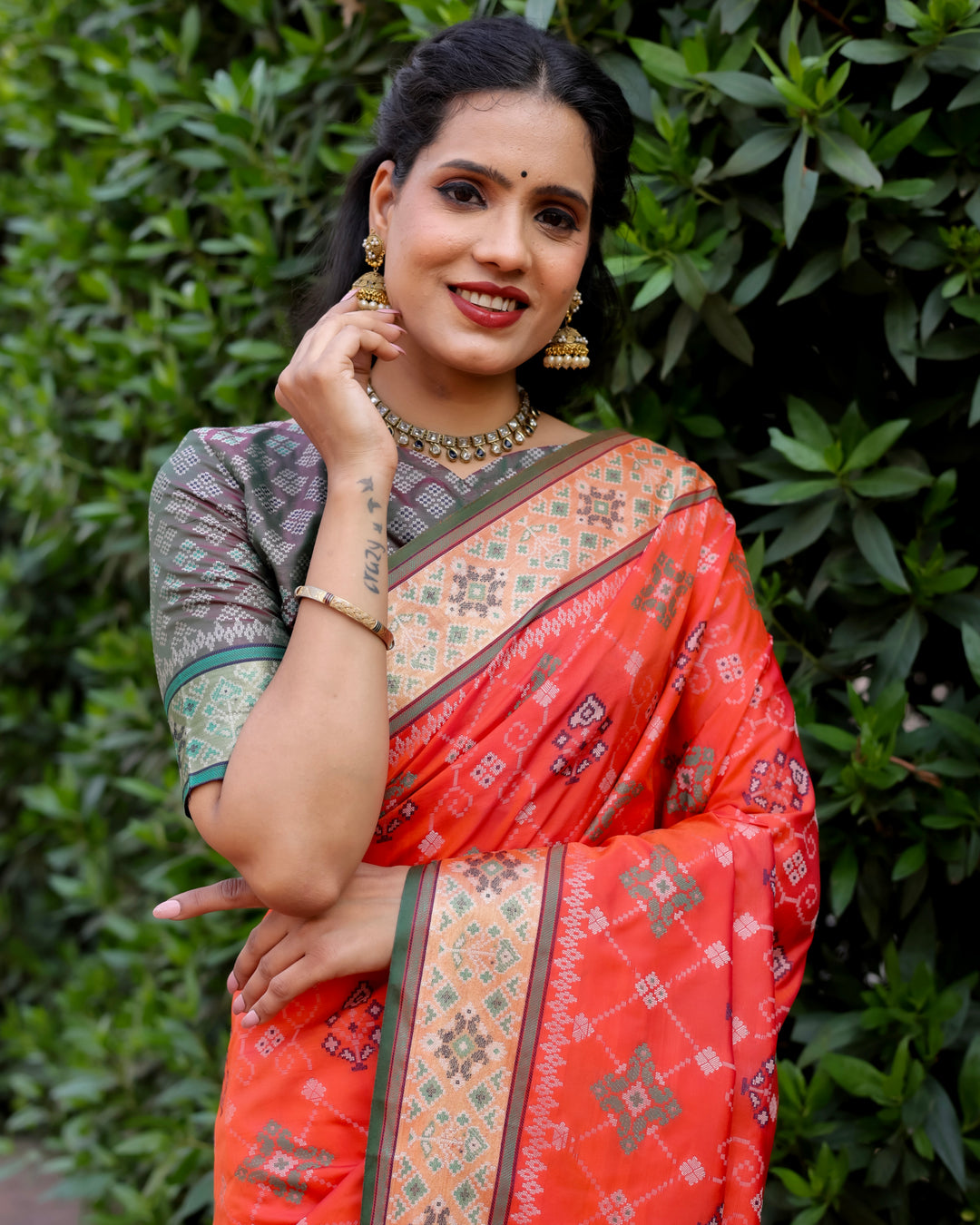 The bold orange Patola silk saree with intricate Ikkat designs and contrast Zari borders offers timeless elegance for every occasion.