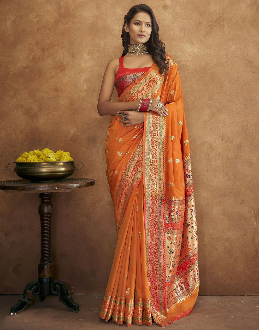 Elegant orange Pethani silk saree with gold zari motifs and Meenakari border for weddings.