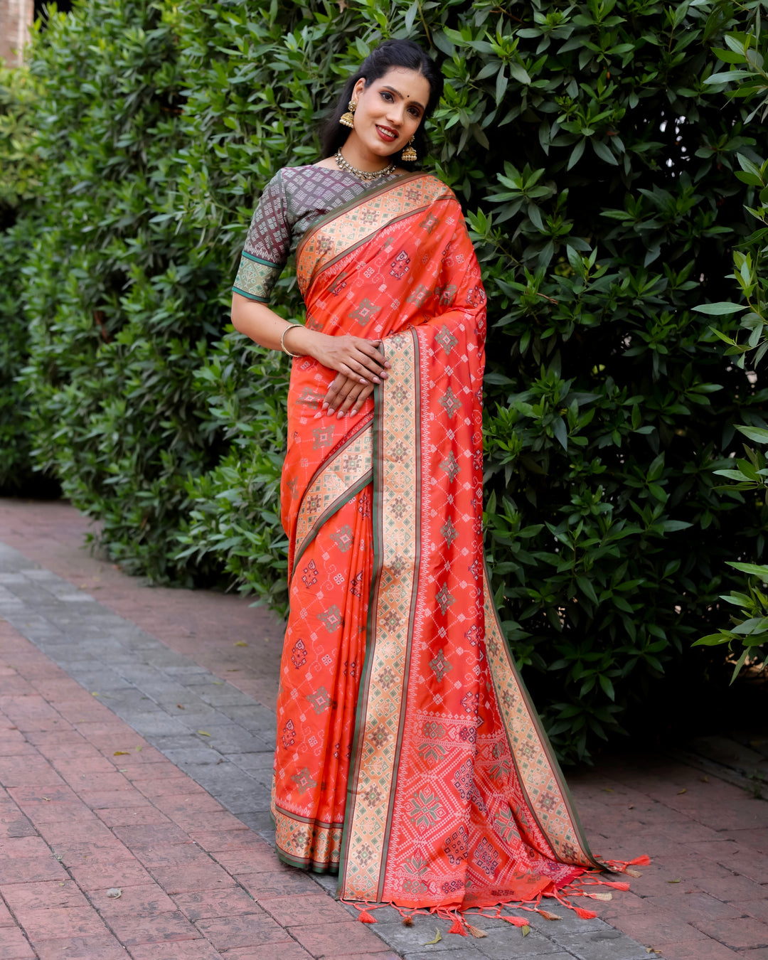 This orange Ikkat Patola silk saree features intricate Ikkat patterns and a vibrant contrast Zari border, ideal for festive celebrations.