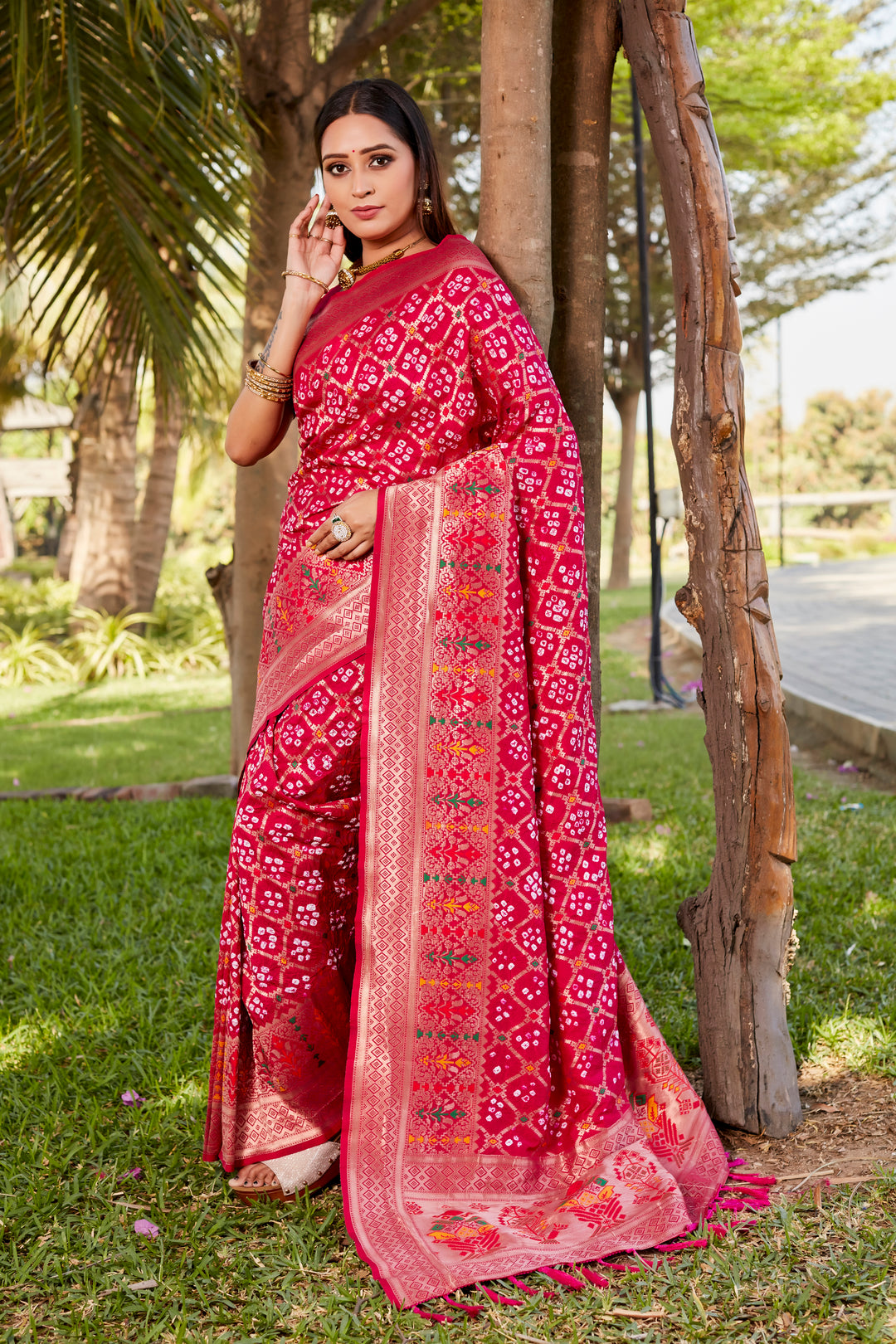 Beautiful hot pink Gharchola Bandhej silk saree with a zari woven border and meenakari detailing, perfect for wedding festivities.