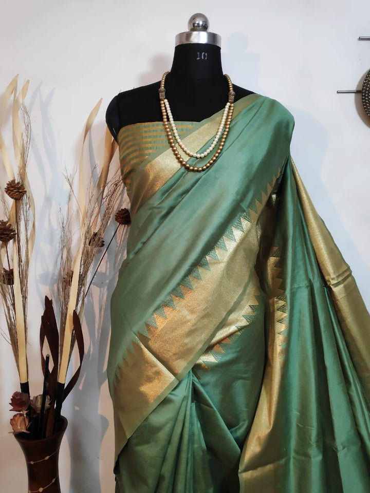 Celebrate tradition in a green Indian sari with a stunning temple border and zari detailing, perfect for ethnic fashion.