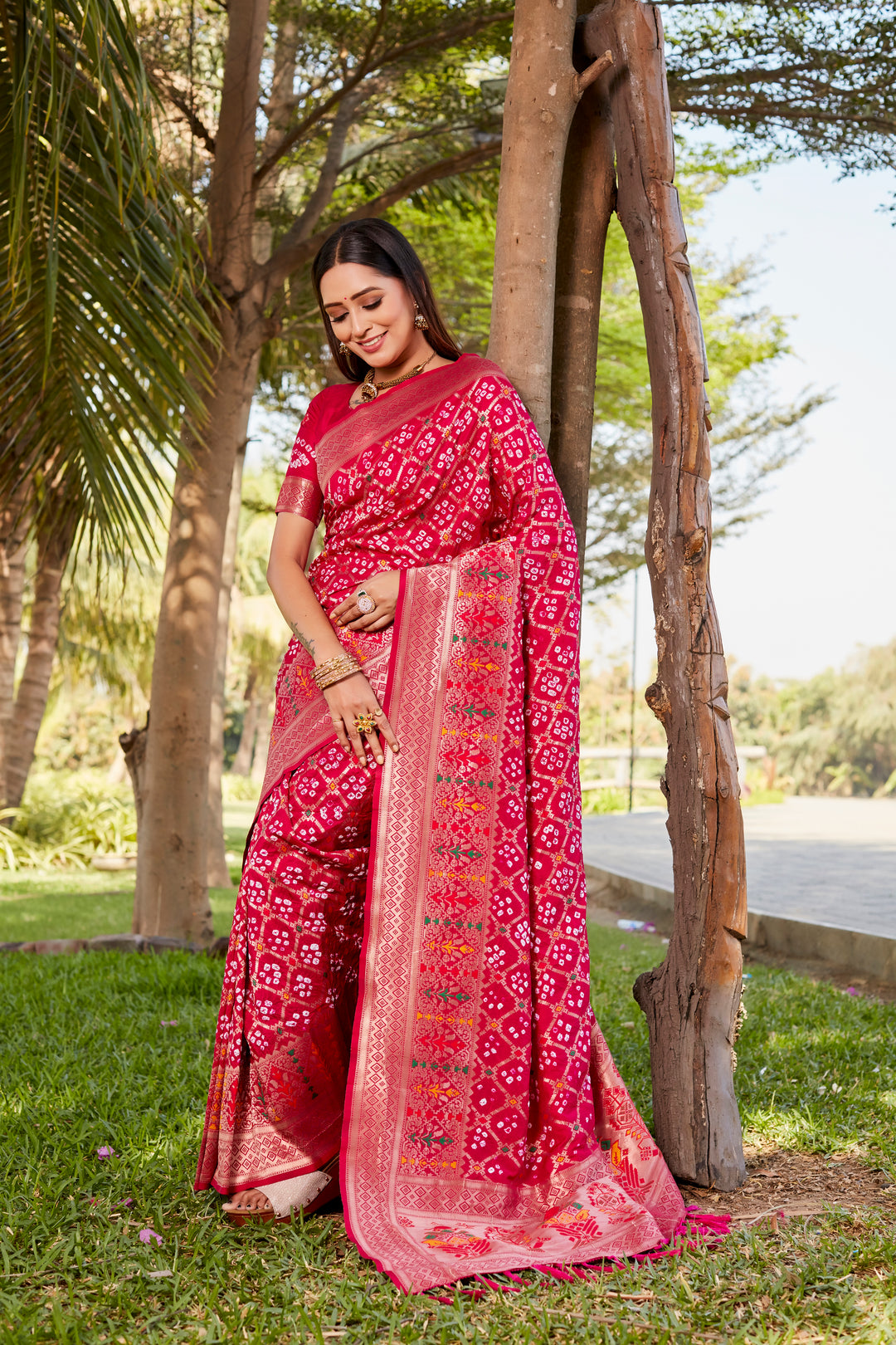 Hot pink Gharchola Bandhej silk saree featuring intricate zari and meenakari borders, ideal for celebrations and cultural gatherings.