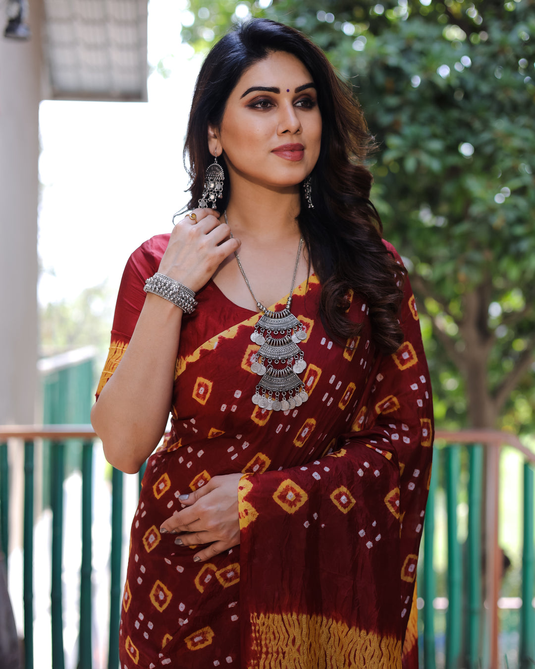 Maroon Bandhej silk saree featuring intricate Zari work and a stunning tissue pallu, ideal for festive occasions.