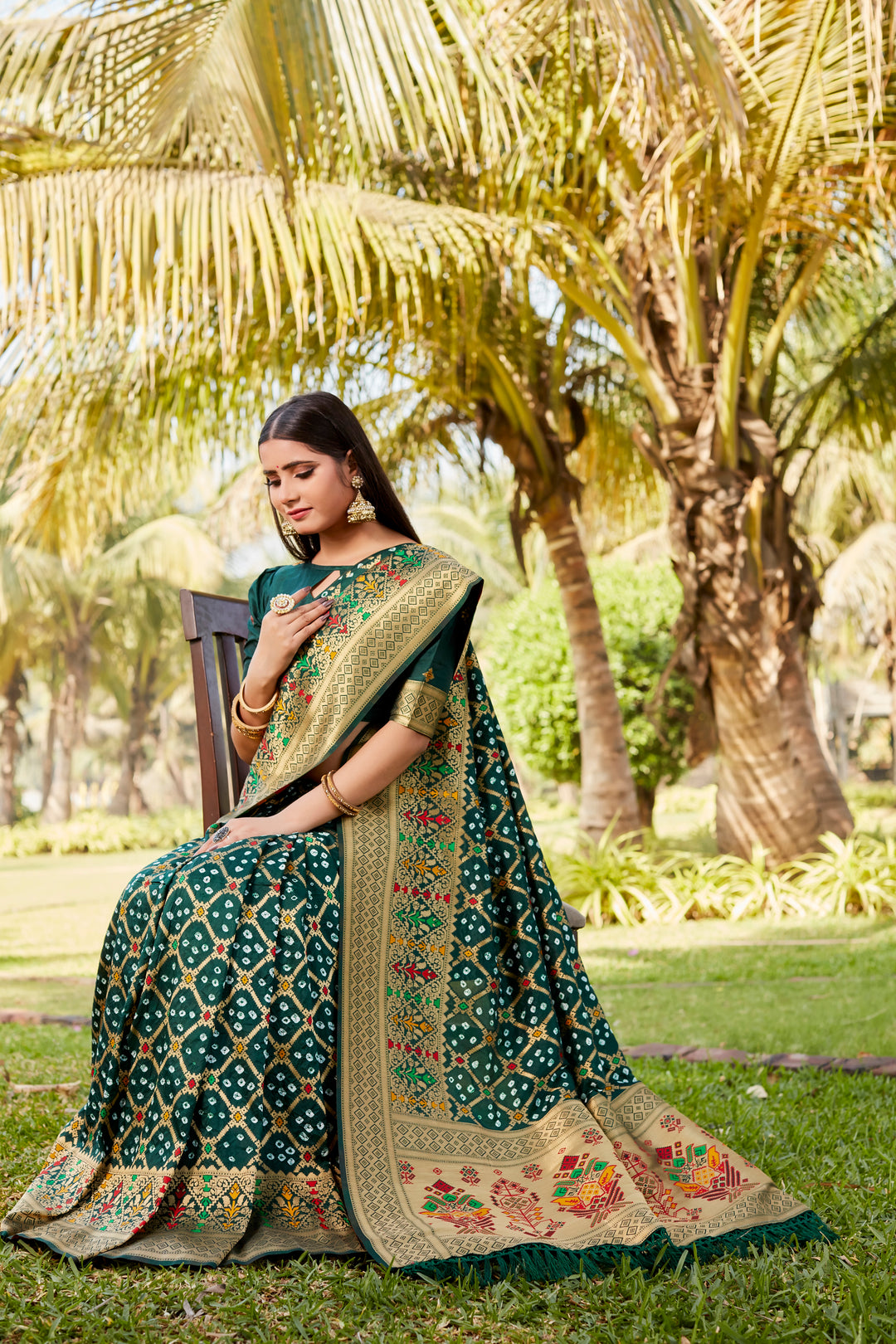 Dark green Gharchola Bandhej silk saree with intricate zari weaving and meenakari borders, perfect for traditional celebrations.