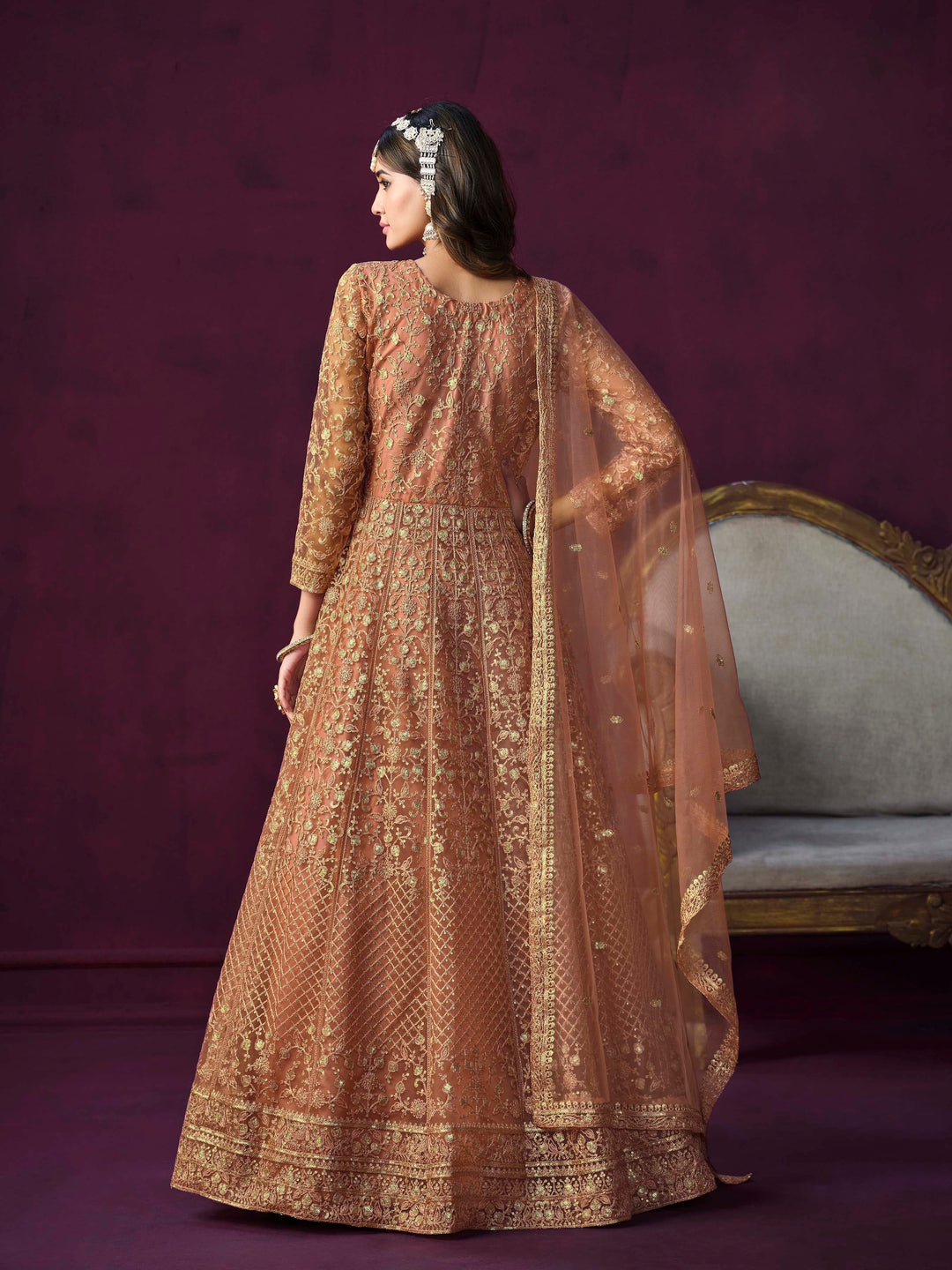 Stylish coral net salwar kameez with intricate embroidery and zari, ideal for festive occasions.