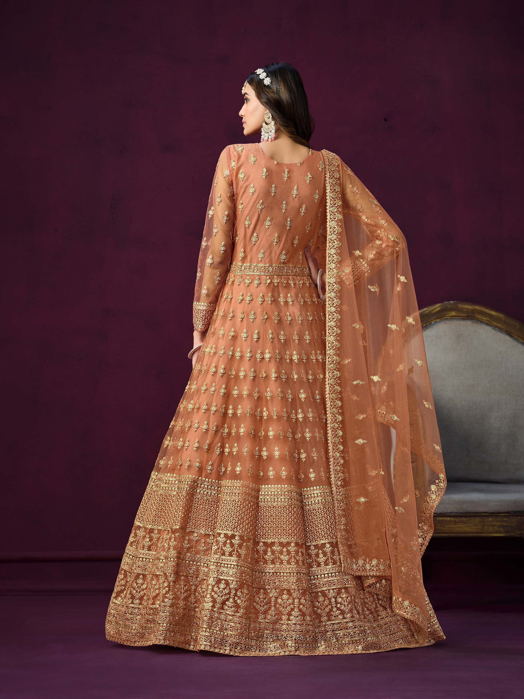 Stylish coral net salwar kameez with intricate embroidery and zari, ideal for festive occasions.