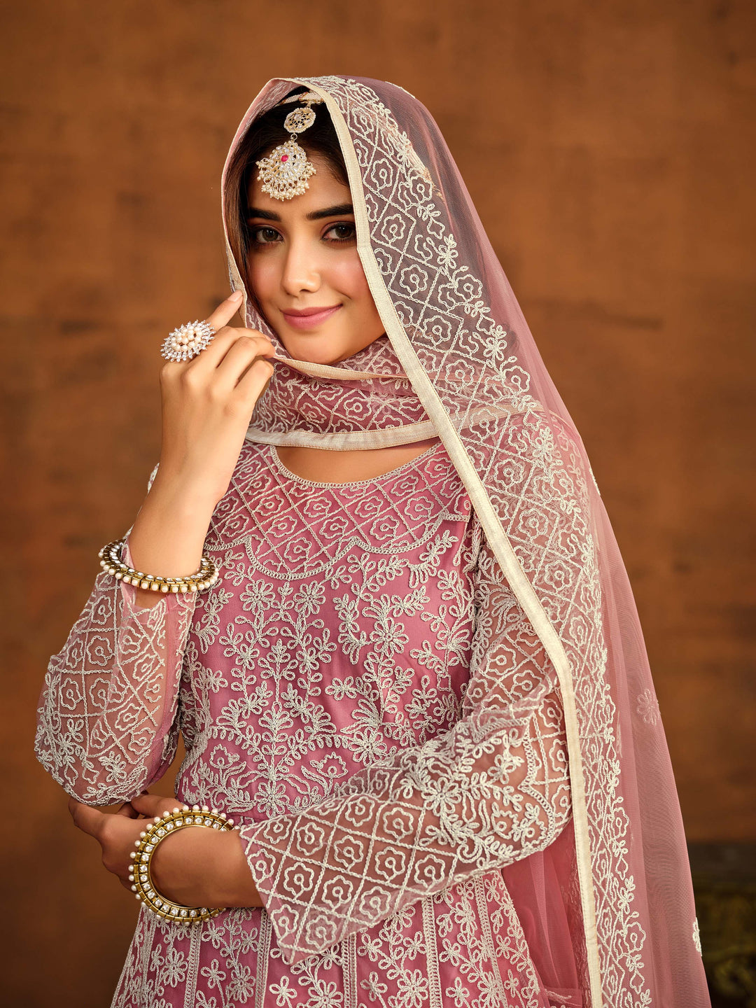 Stylish pink net salwar kameez with intricate embroidery work, ideal for festive occasions.