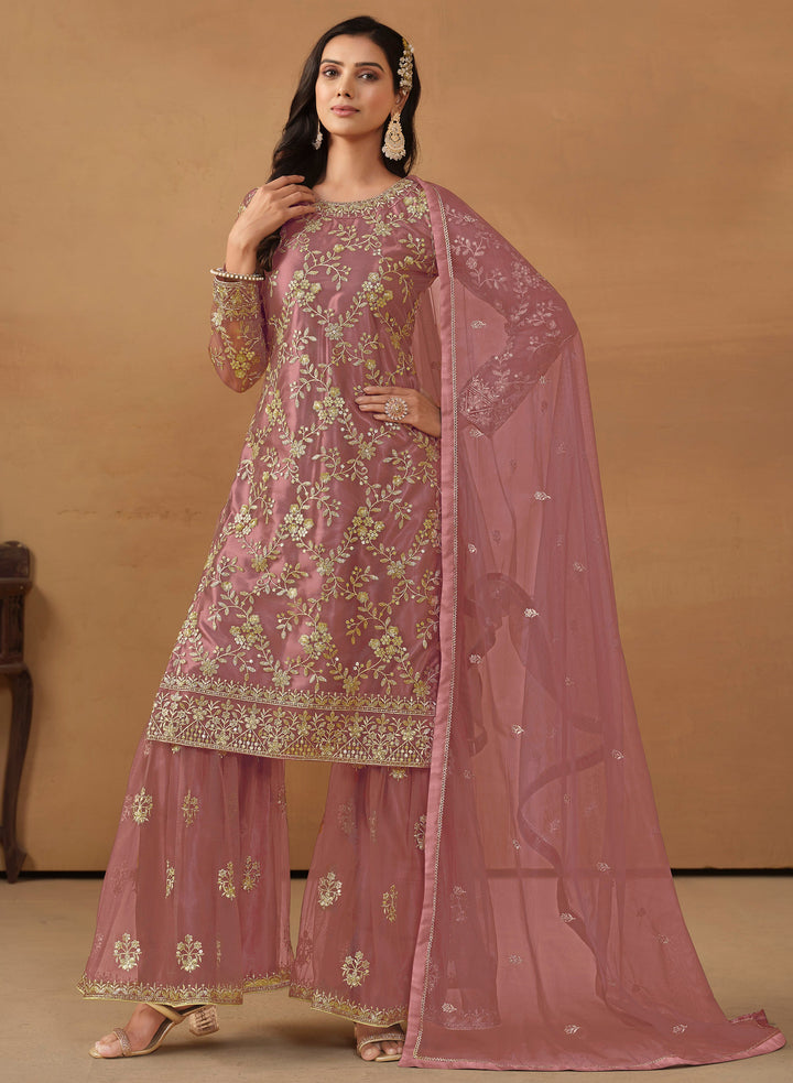 Stunning dusty pink salwar kameez in net with intricate thread embroidery and shimmering sequin work for festive events.