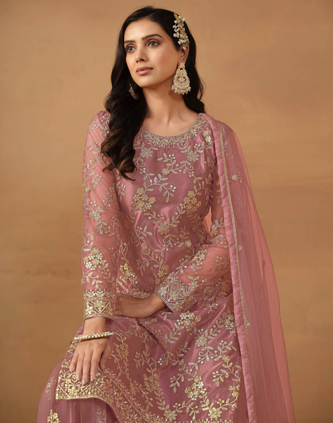 Luxurious dusty pink net salwar kameez adorned with exquisite heavy embroidery and sequins, ideal for weddings and celebrations.