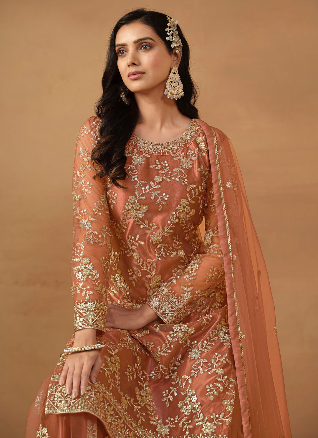 Luxurious dark salmon net salwar kameez adorned with exquisite heavy embroidery and sequins, ideal for weddings and celebrations.