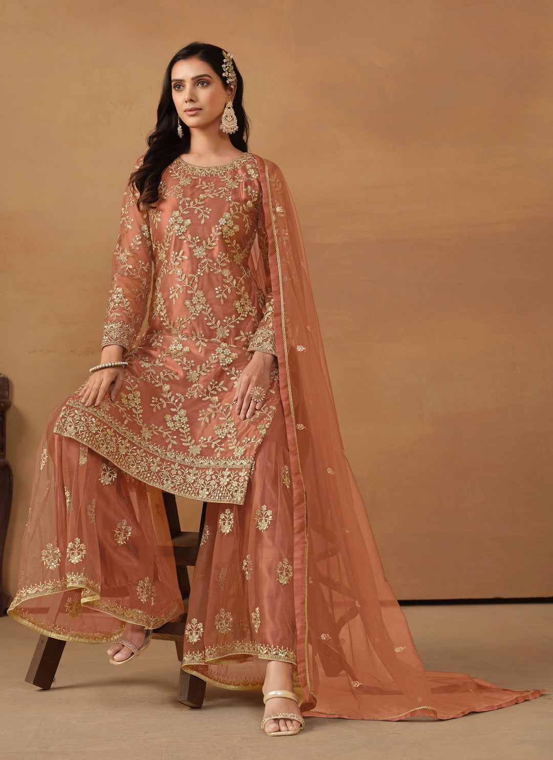 Beautiful dark salmon salwar kameez crafted from net, showcasing intricate heavy thread and sequin embellishments.