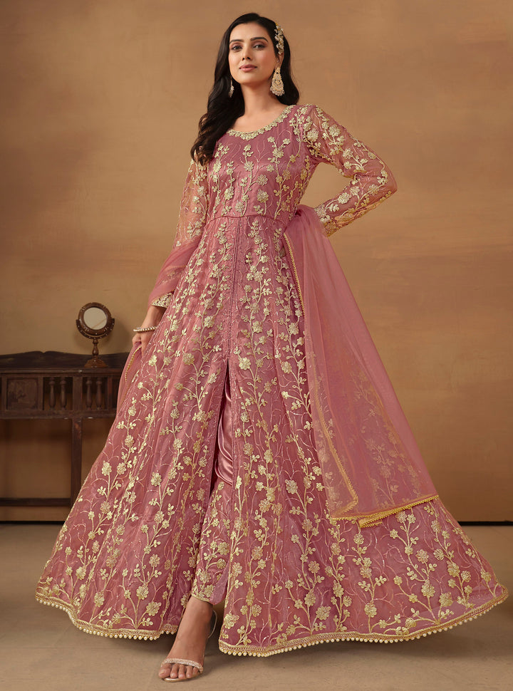 Elegant dusty pink net salwar kameez featuring heavy thread embroidery and sequins, perfect for special occasions.