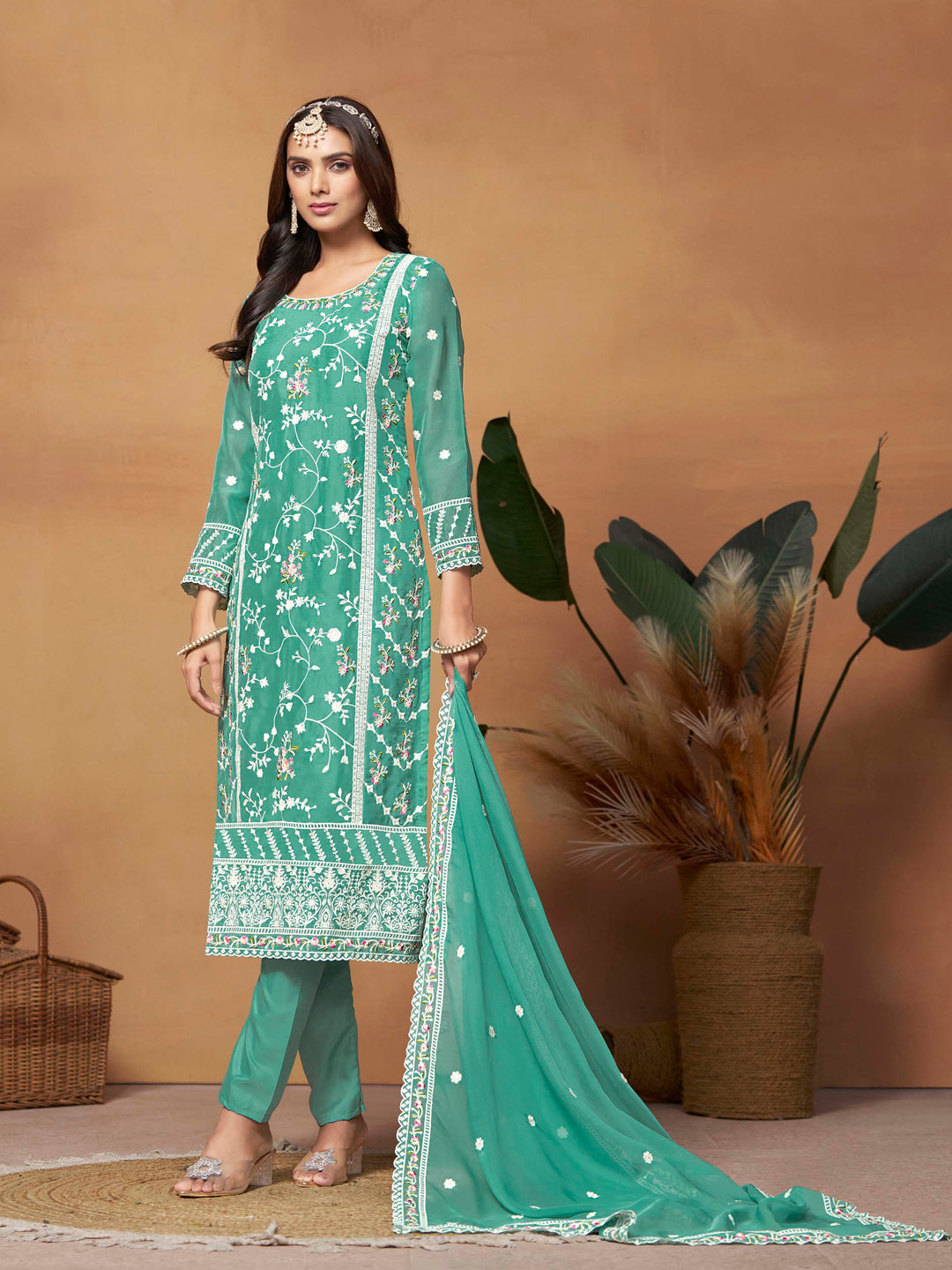 Stunning turquoise salwar kameez in soft organza with intricate thread embroidery and shimmering sequin work for special events.