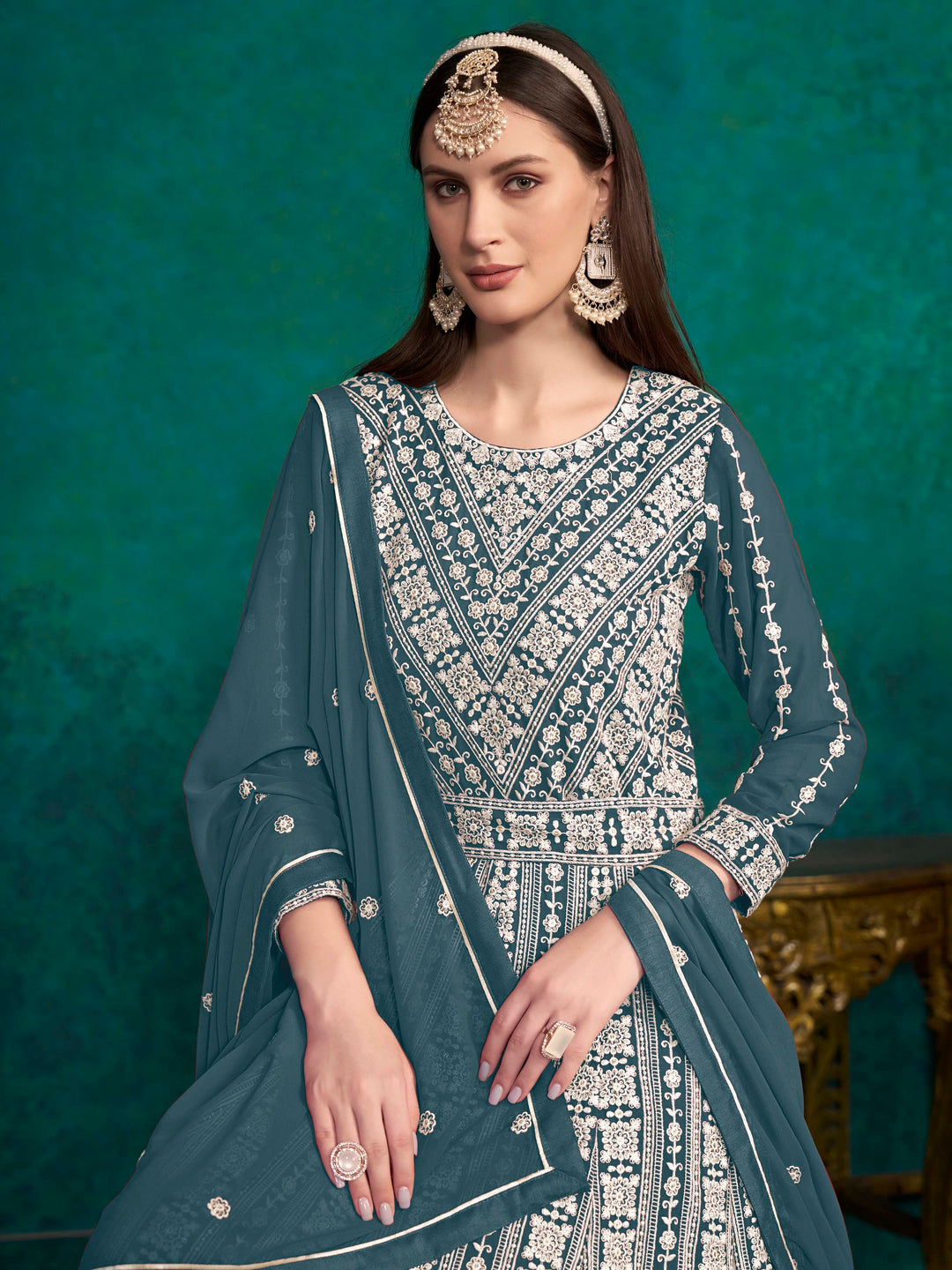 Stunning teal blue salwar kameez in faux georgette, showcasing heavy thread embroidery and shimmering sequins for celebrations.