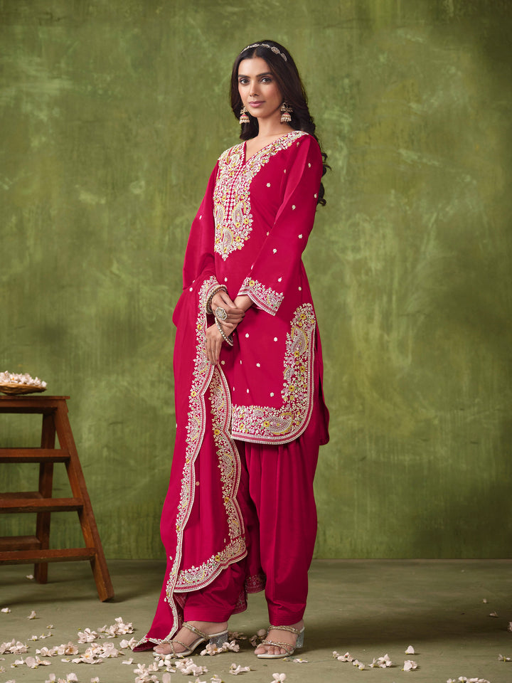 Vibrant rani pink salwar kameez in Roman silk with heavy thread embroidery and sequins, perfect for weddings and celebrations.