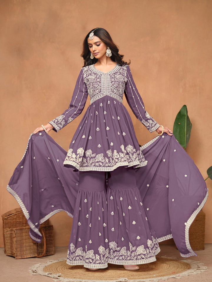 Stylish purple faux georgette salwar kameez adorned with beautiful heavy thread embroidery and free size sharara bottom for festive occasions.