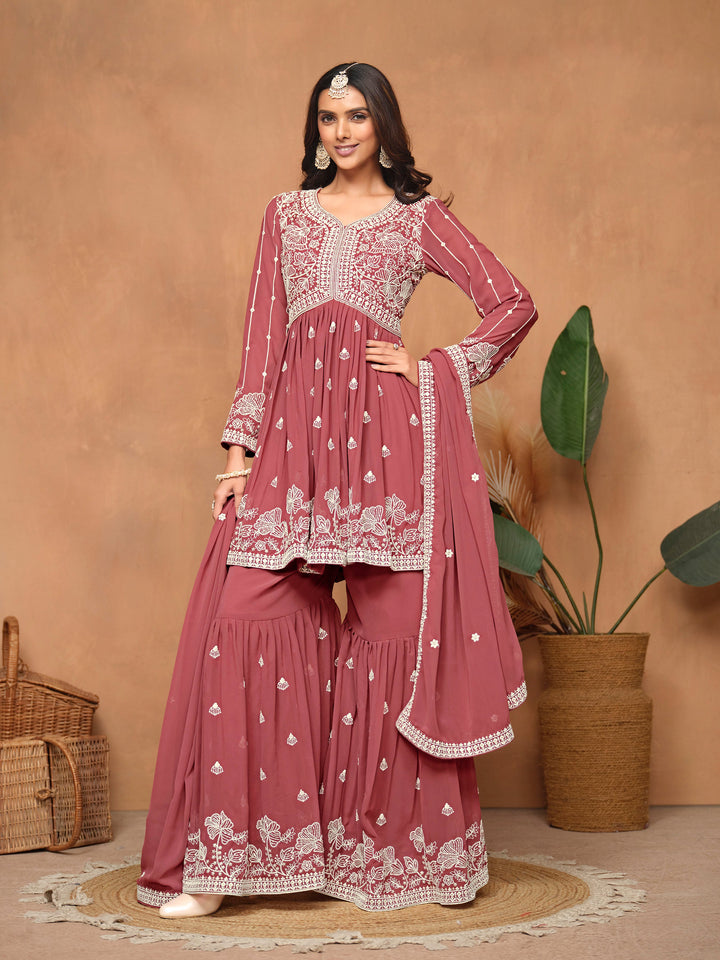 Elegant dark rose faux georgette salwar kameez featuring intricate heavy thread embroidery and sharara bottom for festive occasions.