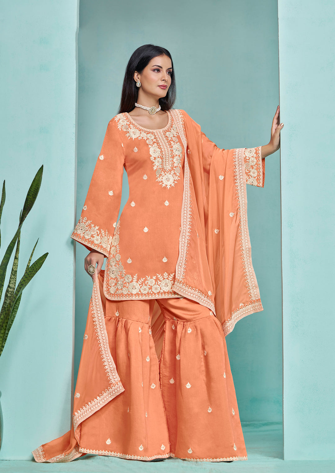 Beautiful light orange Roman silk salwar kameez adorned with heavy thread embroidery and sequins, designed with a sharara bottom.