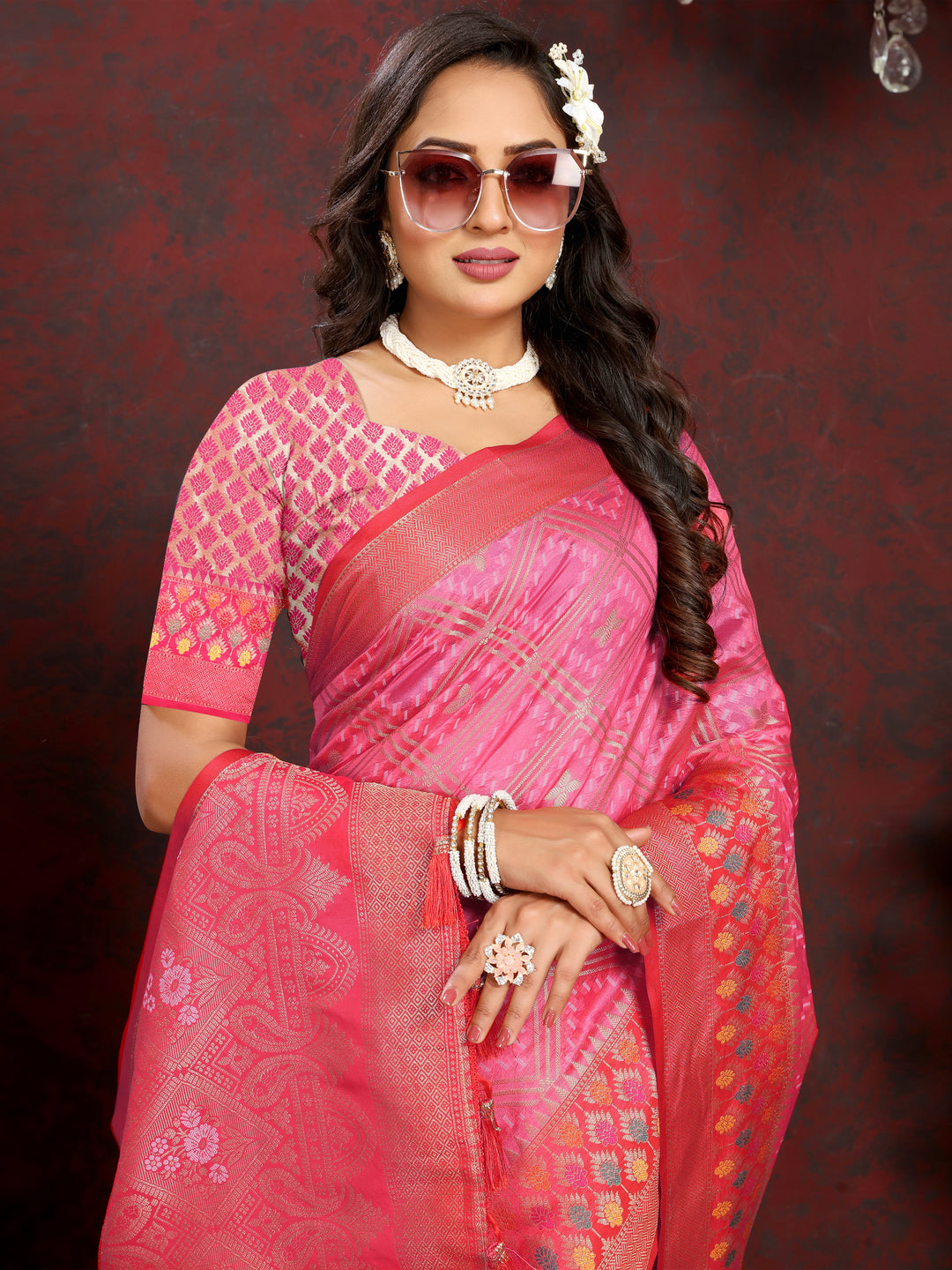 Classic coral pink Organza silk saree with detailed zari weaving and Meenakari artistry, ideal for festive gatherings.