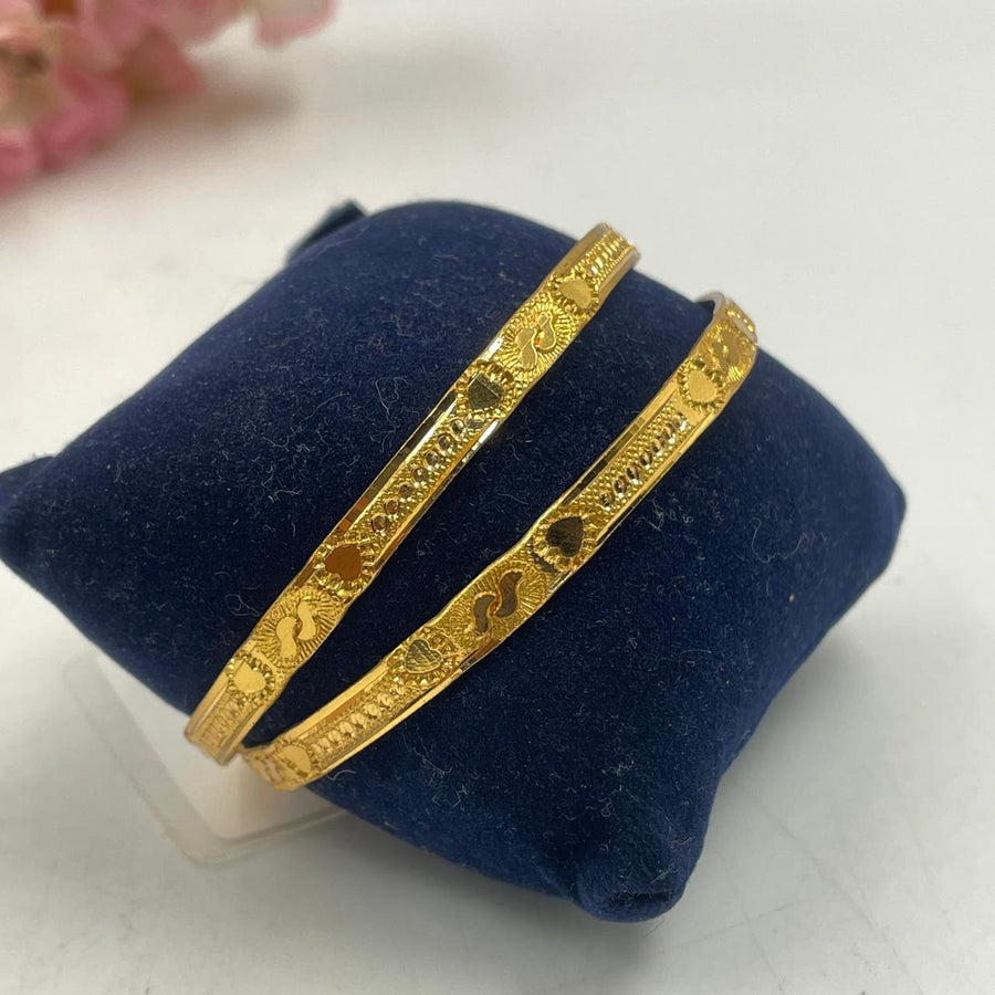 Charming golden bangles featuring delicate engravings.