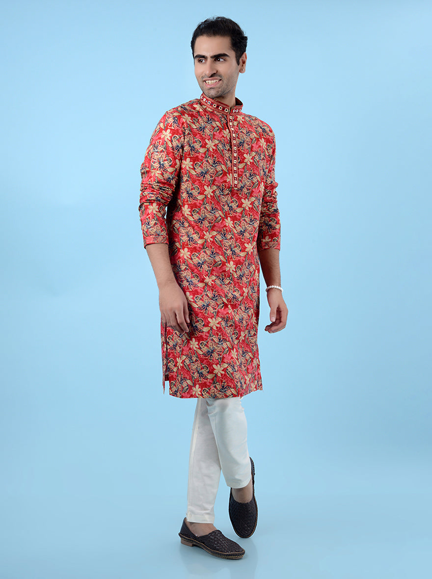 Men's red ethnic kurta pajama set with vibrant prints and mirror work, ideal for cultural occasions.