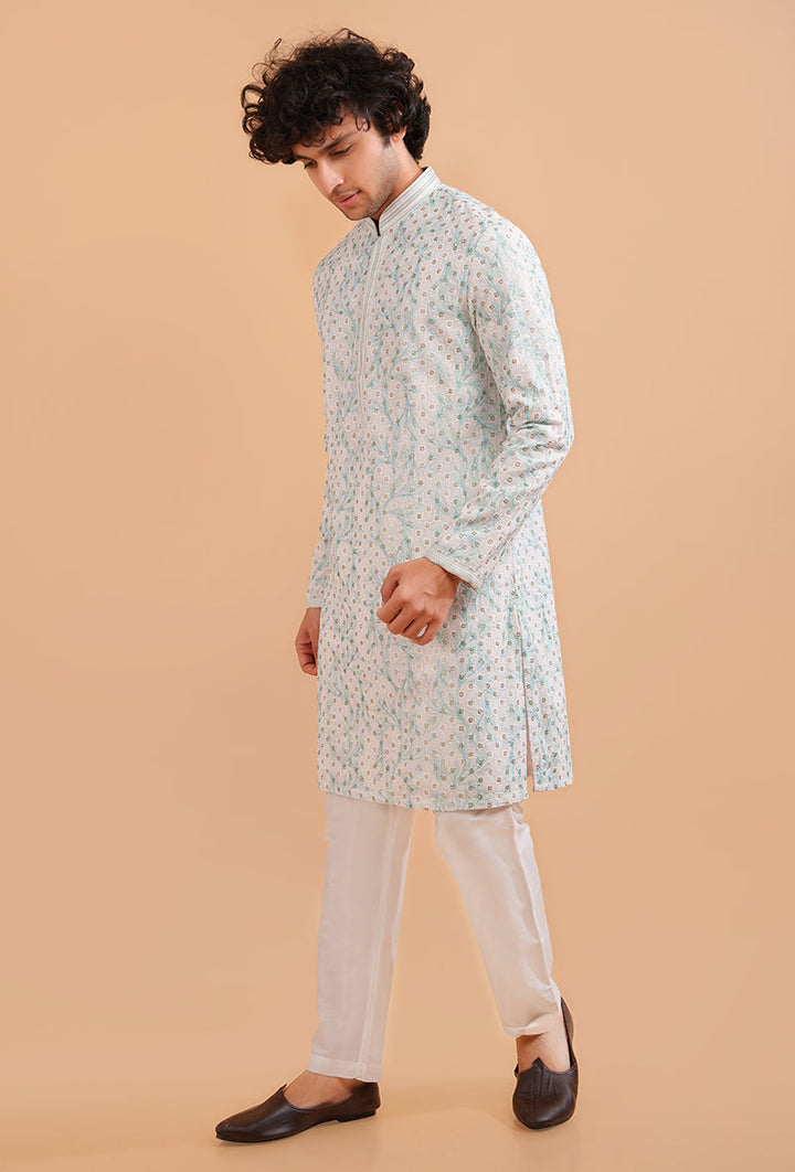 Premium white silk blend kurta pajama set for men with intricate green threadwork for festive occasions.