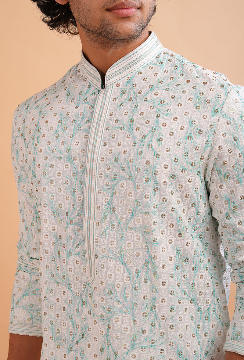 Elegant white silk blend kurta pajama set for men, adorned with green threadwork for cultural events.