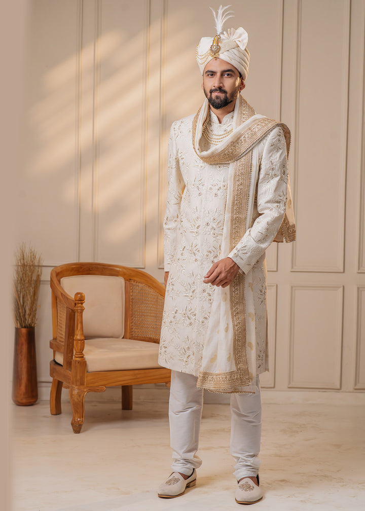 Elevate your wedding attire with this ivory sherwani set, adorned with intricate floral embroidery and zardosi details, ensuring a regal appearance.