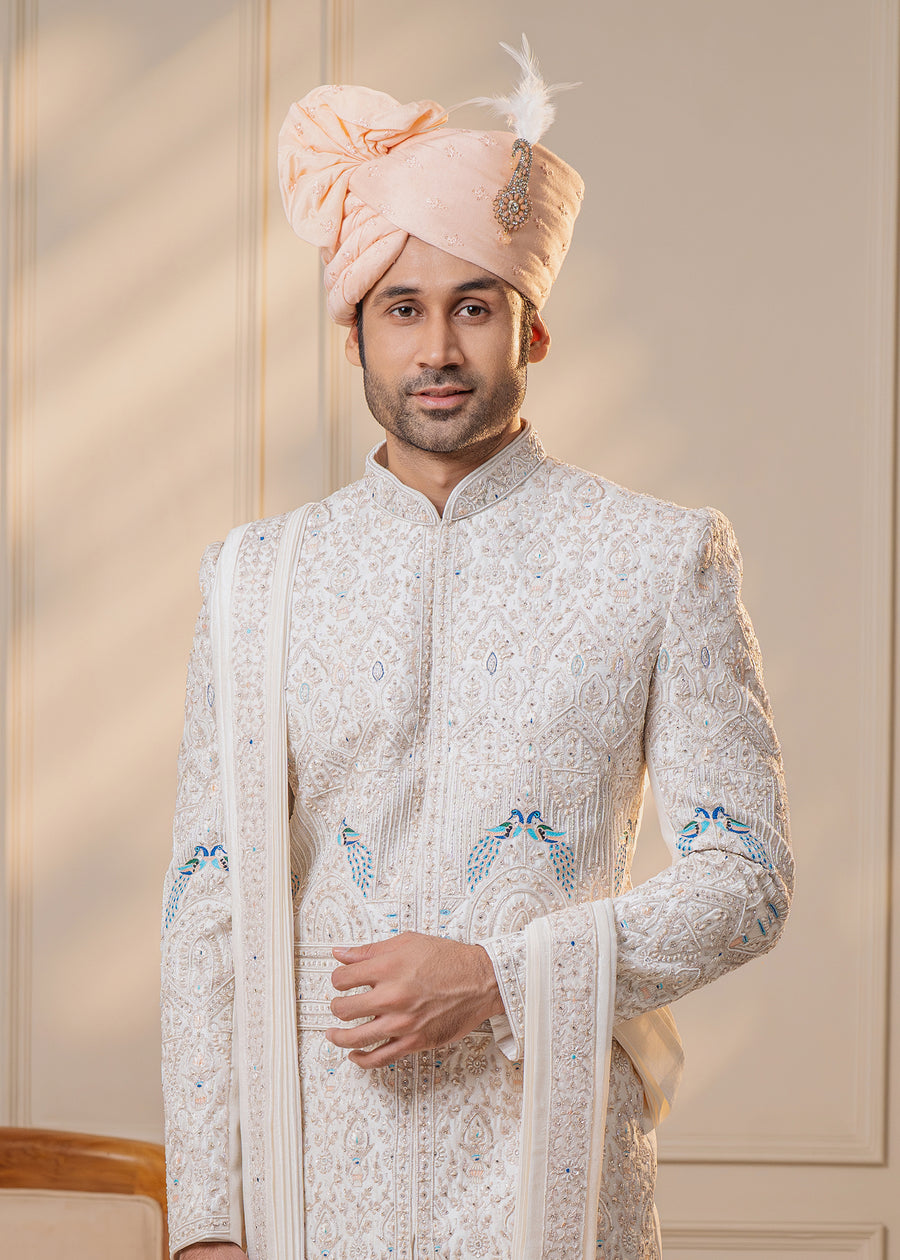 This classic white sherwani features exquisite embroidery and cut-dana details, perfect for grooms in the USA seeking rich craftsmanship and style.