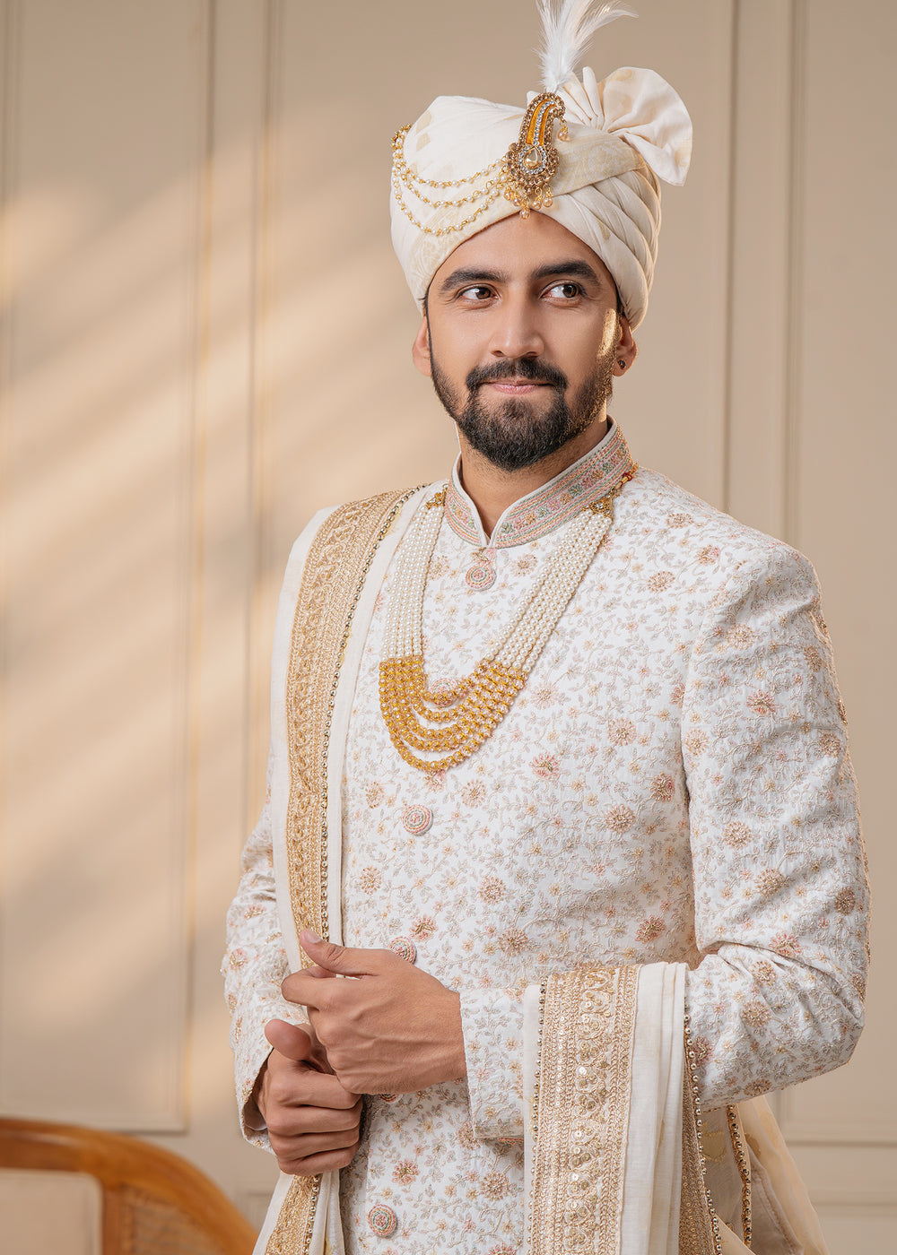 This elegant off-white sherwani combines classic design with sophisticated zari work and subtle peach accents.