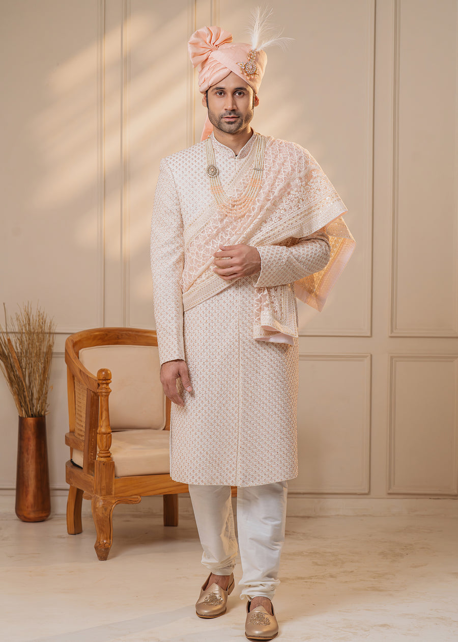 This off-white sherwani features stunning rose gold zardosi and cut-dana details, ideal for weddings.