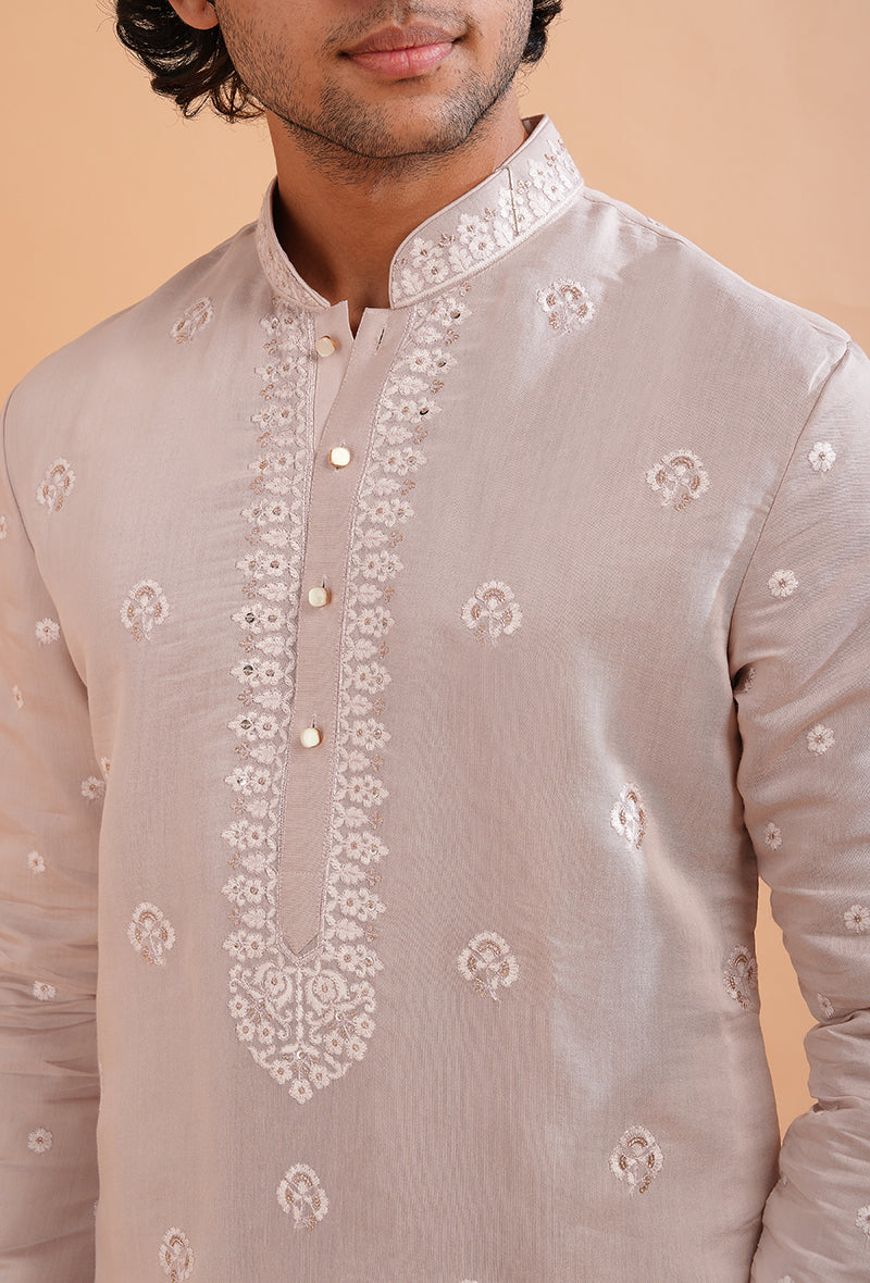 Traditional pale pink kurta pajama set for men, designed with detailed embroidery.