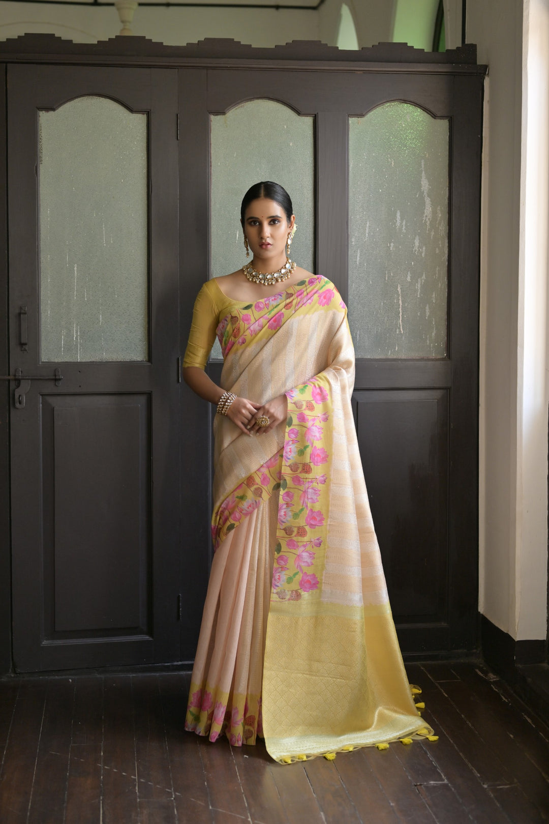 Vibrant coral-orange soft silk saree featuring Pichwai lotus print and luxurious zari pallu, perfect for bridal wear.