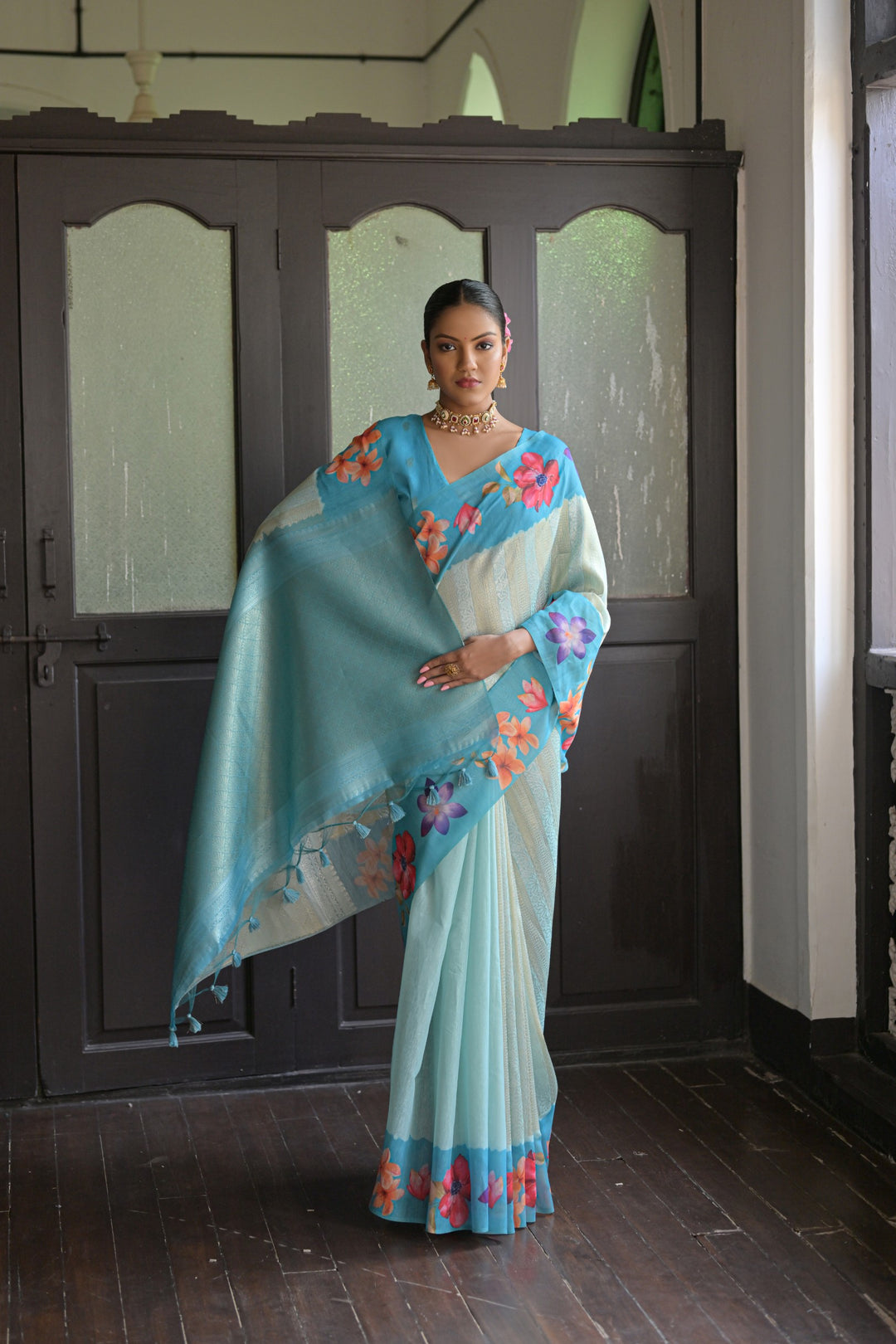 Charming sky-blue silk saree with flower prints and a fancy lotus pallu, ideal for traditional celebrations.