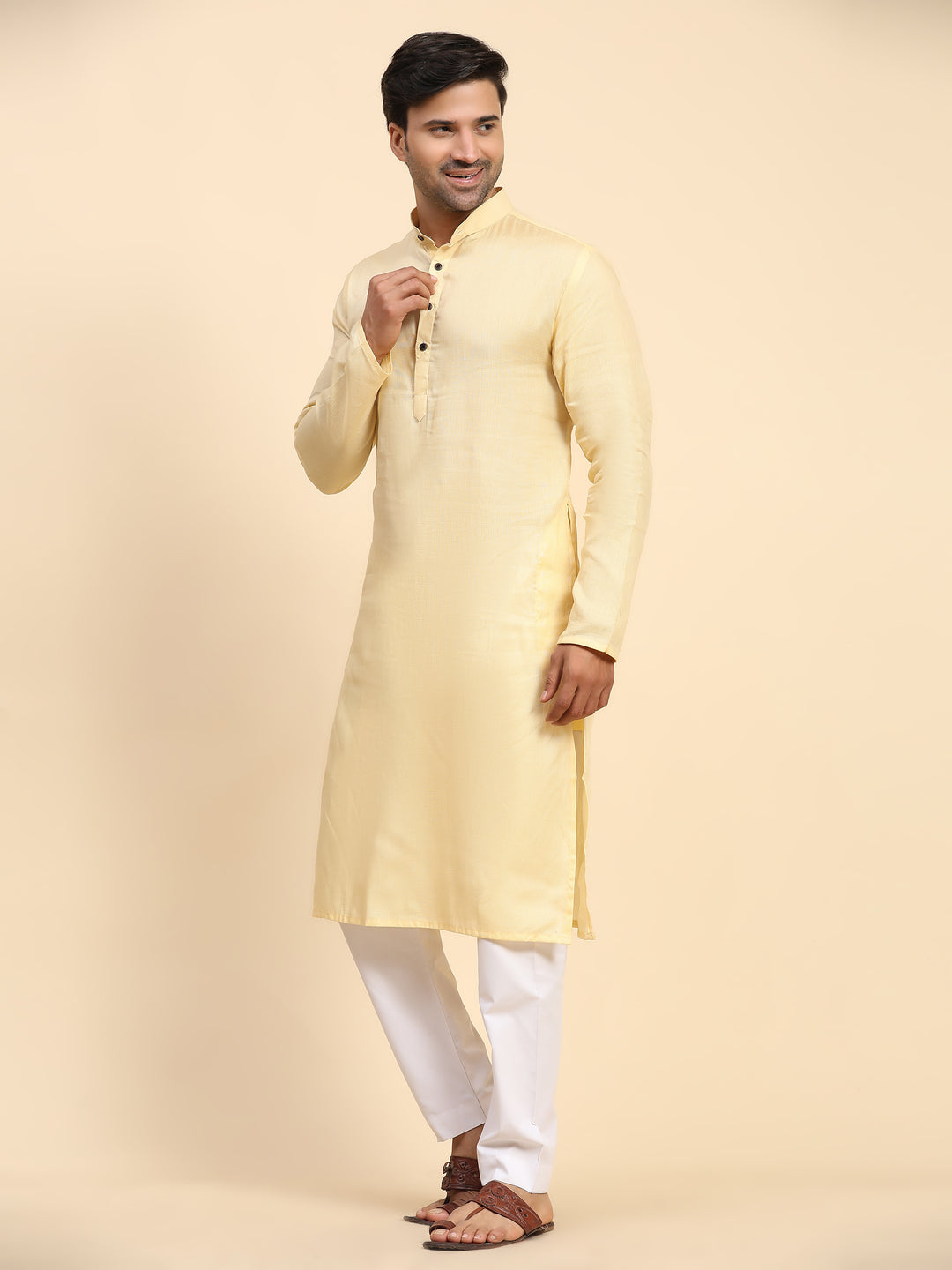 Men’s creamish yellow kurta pajama set with intricate embroidery, ideal for festive occasions.