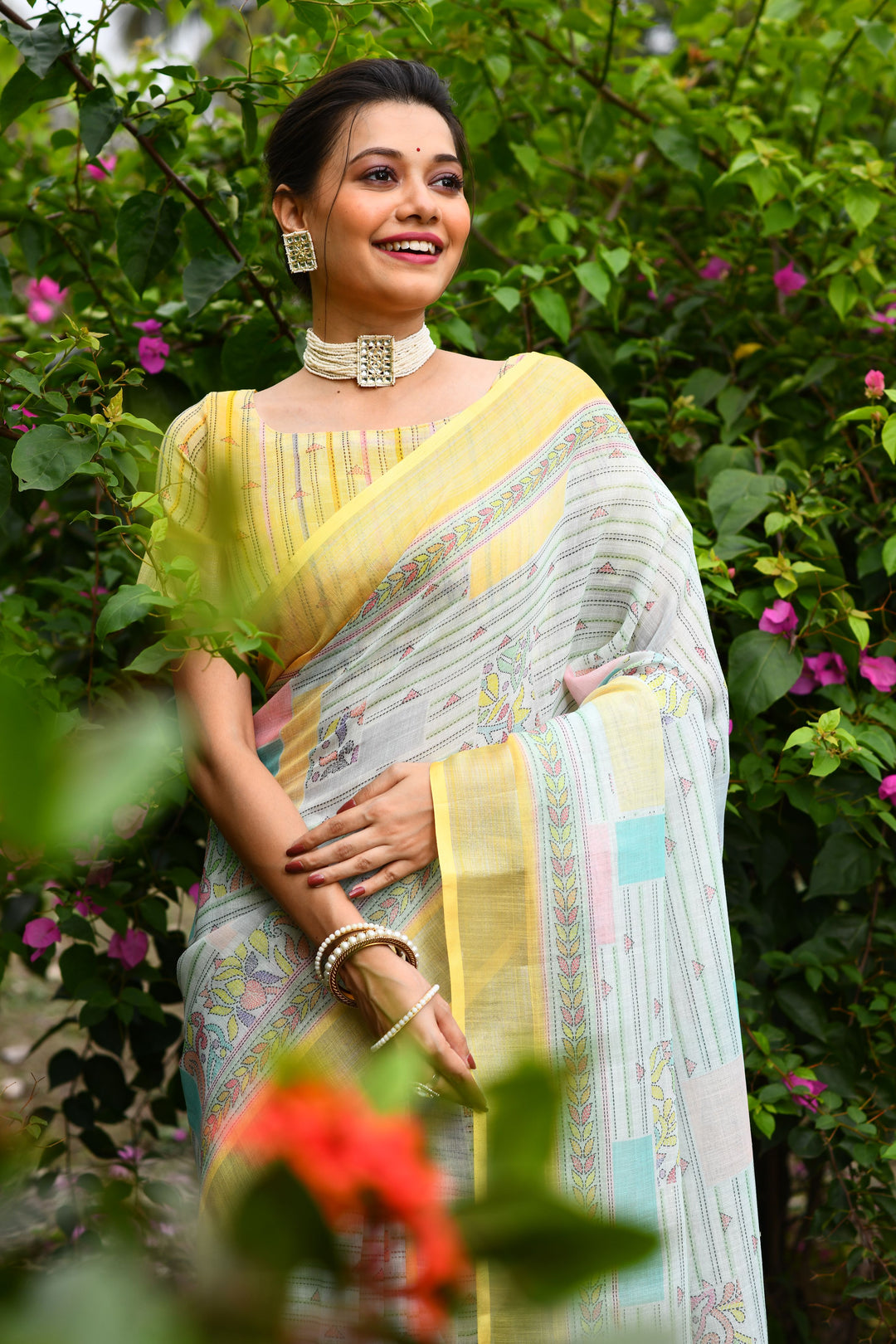 Bright yellow linen saree with a floral pallu and elegant cotton bundas details, ideal for festive and casual events.