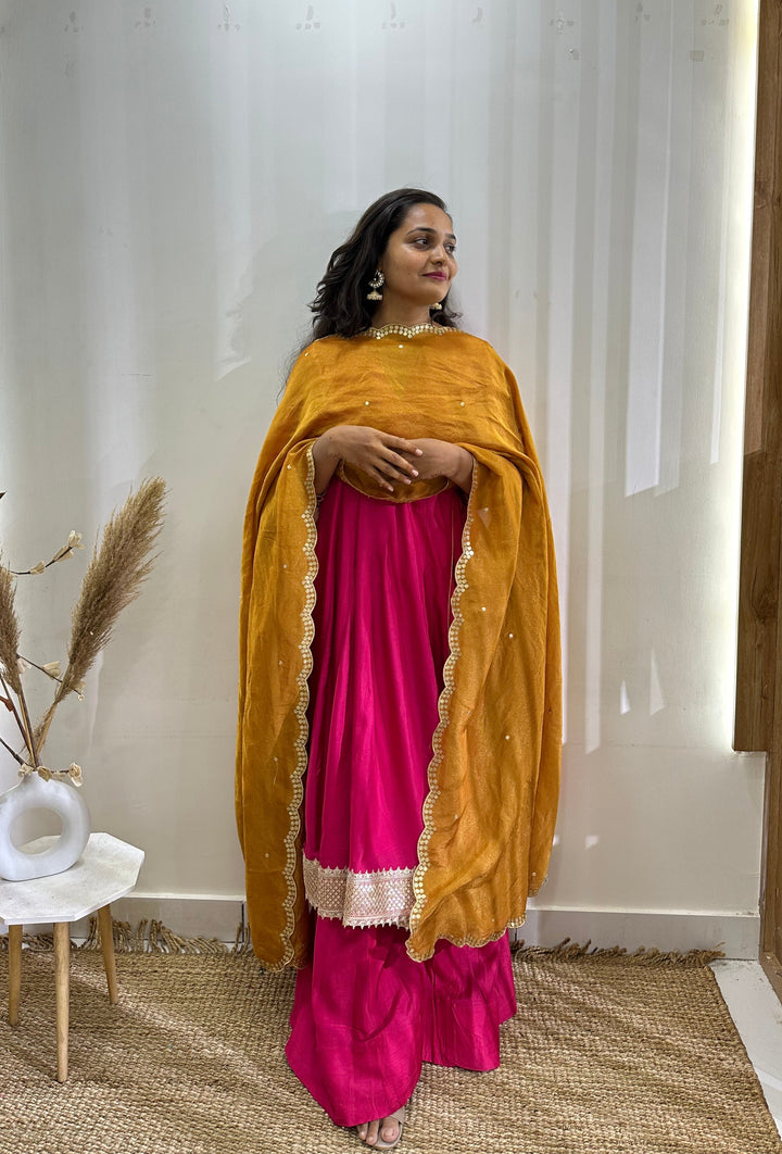 Stunning hot pink Anarkali dress in Angrakha style, paired with a contrasting tissue dupatta for added elegance.