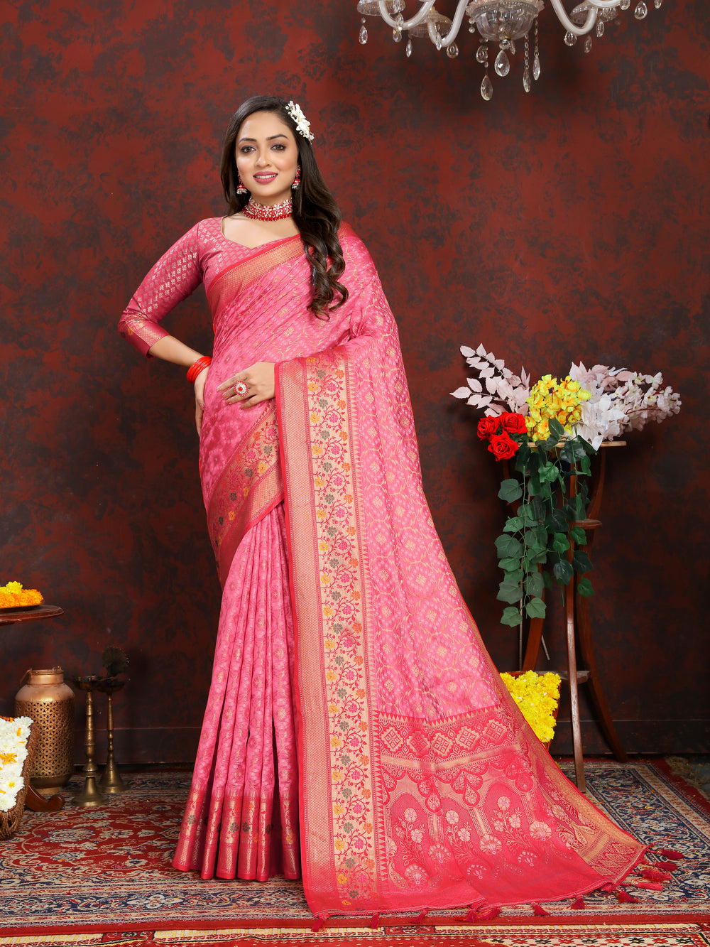 Elegant coral pink saree in organza silk with intricate Meenakari work, adorned with a zari border and pallu tassels.