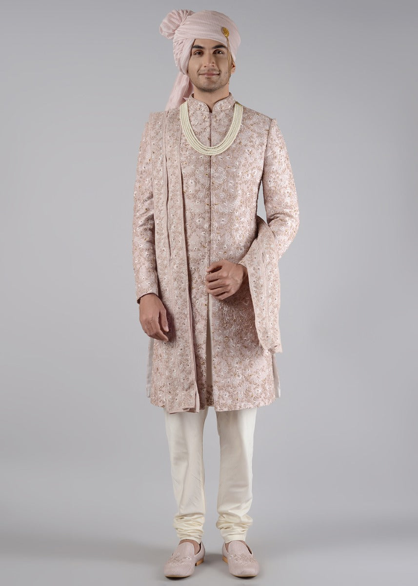 This pink sherwani, crafted from raw silk, features elegant threadwork for a stunning traditional look.